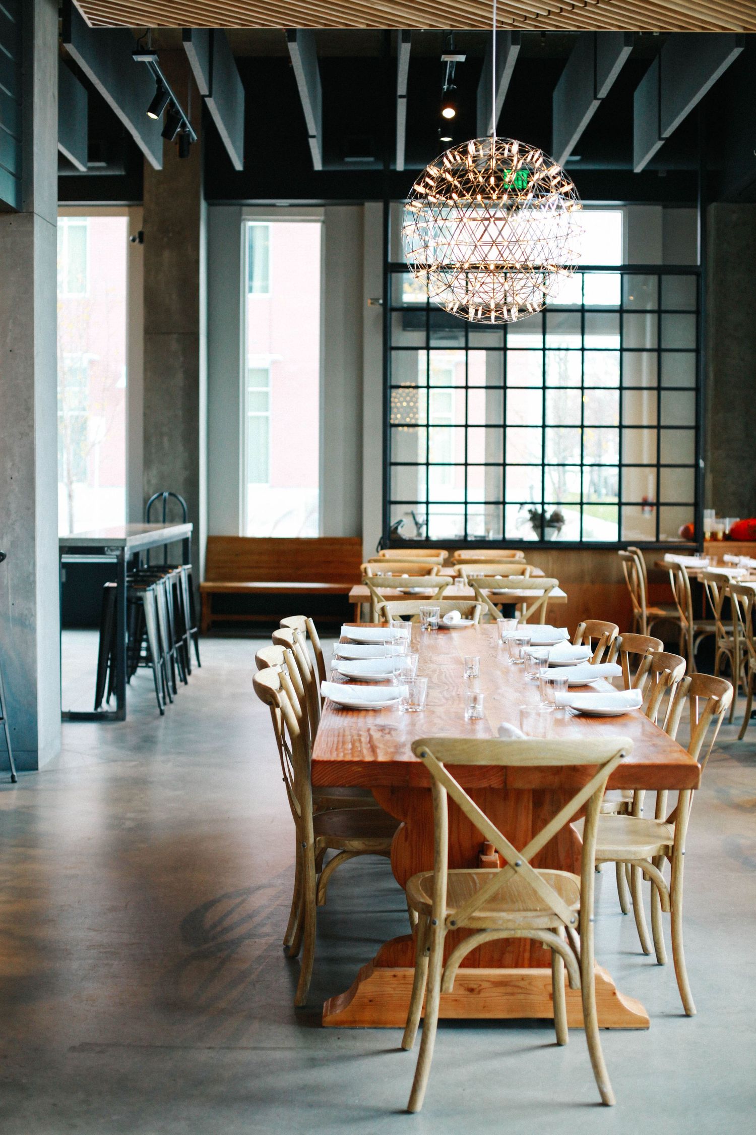 Modern restaurant interior with wooden tables and statement chandelier lighting.