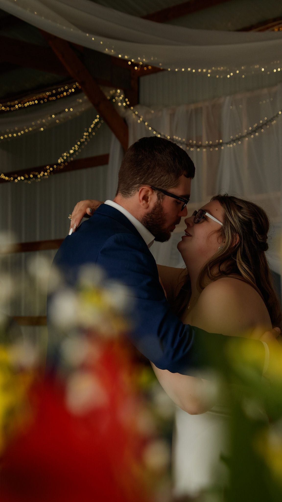 Intimate wedding moment under twinkling lights and decorative indoor reception venue decor.