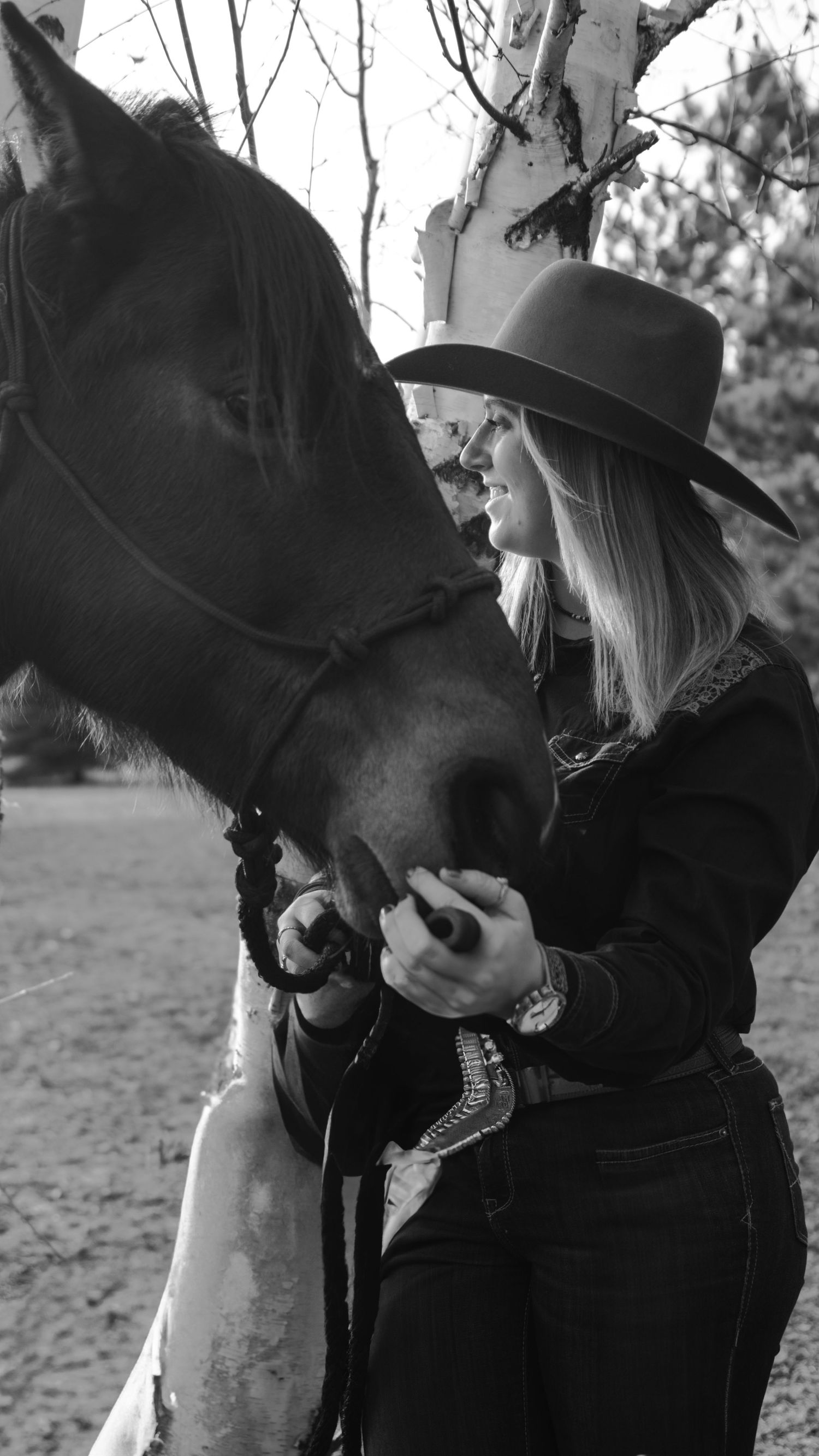 An intimate black and white photo showing tender interaction between a person and horse.