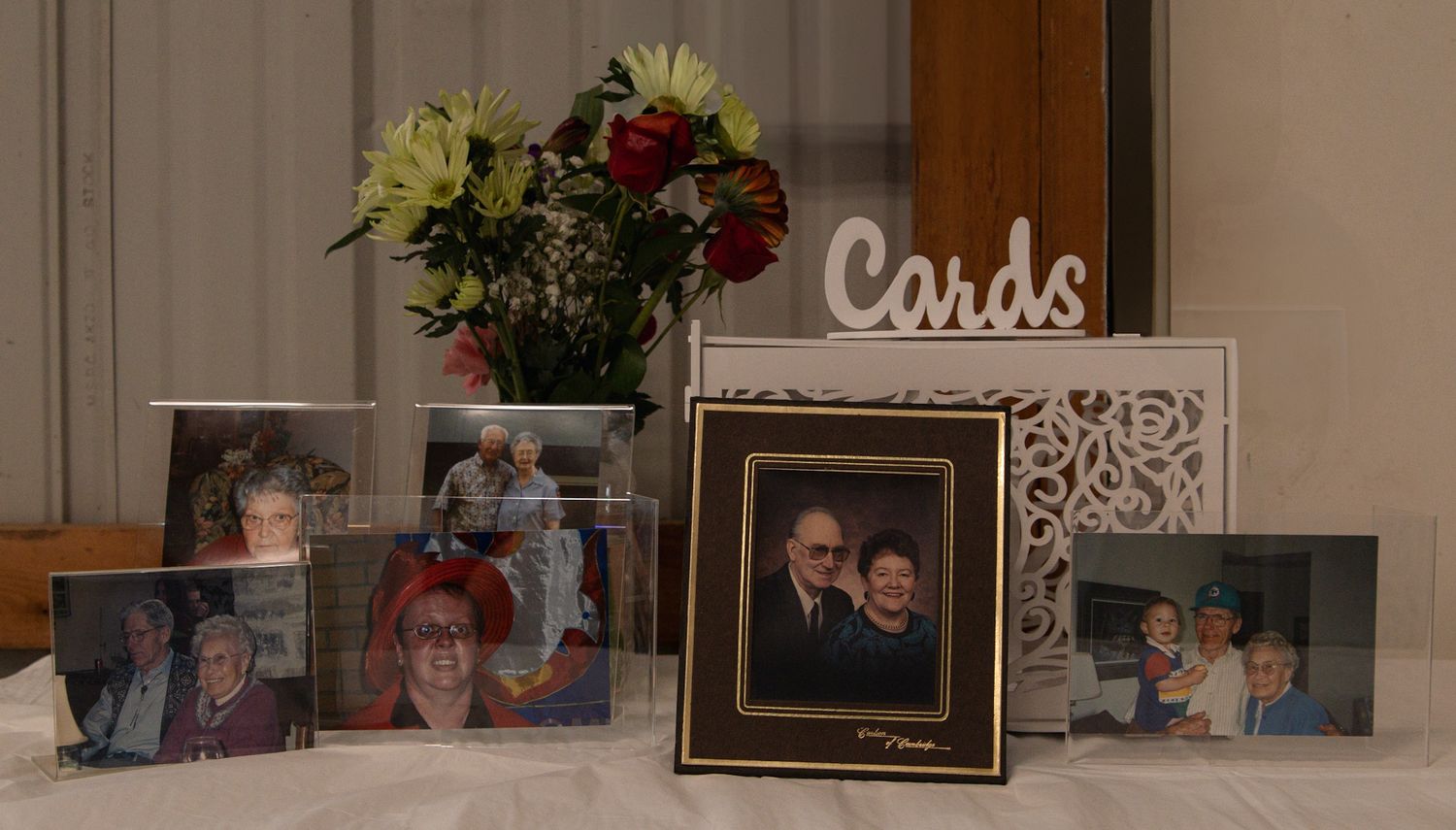Hallway wall decorated with family photos and a handmade 'Cards' sign displayed on a wooden ledge.