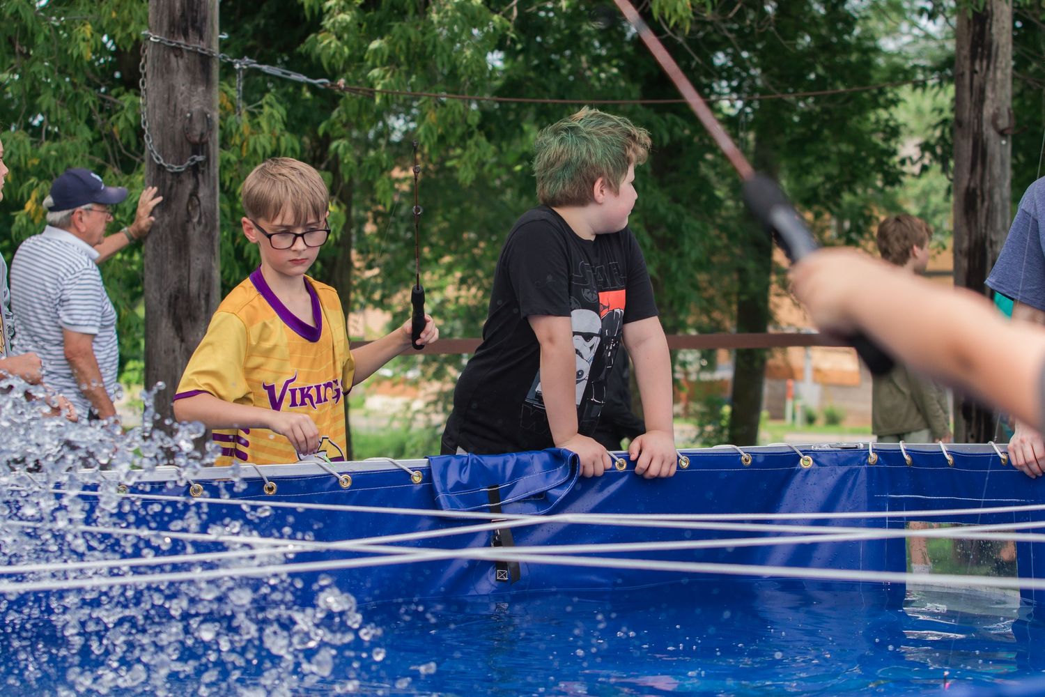 People gathered around outdoor tables with blue coverings during a summer event.