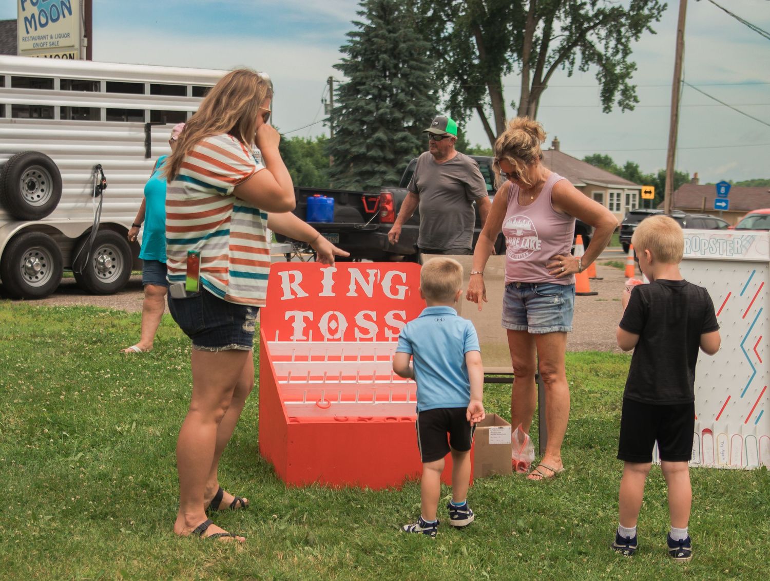 People gathered outdoors around a red promotional display tent at a summer event.