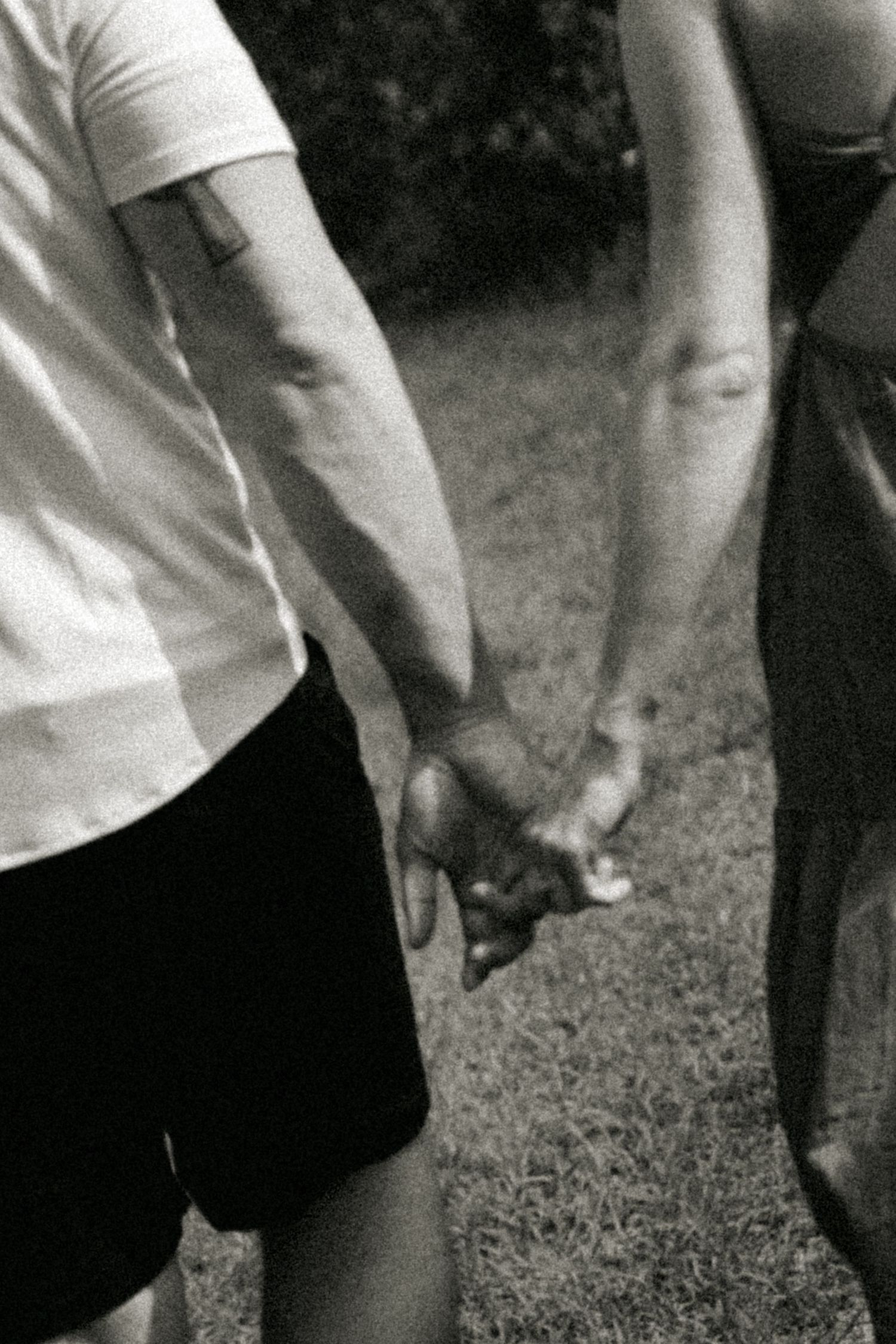 Close-up black and white view of hands gripping a soccer ball on grassy ground during sports practice.