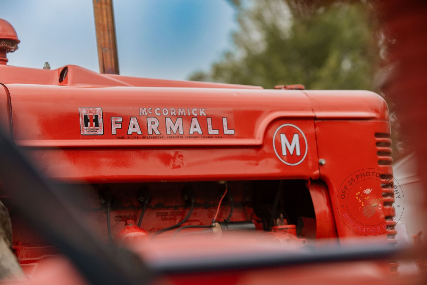 Close-up view of a vintage red Farmall M tractor showing the iconic lettering on its side panel.