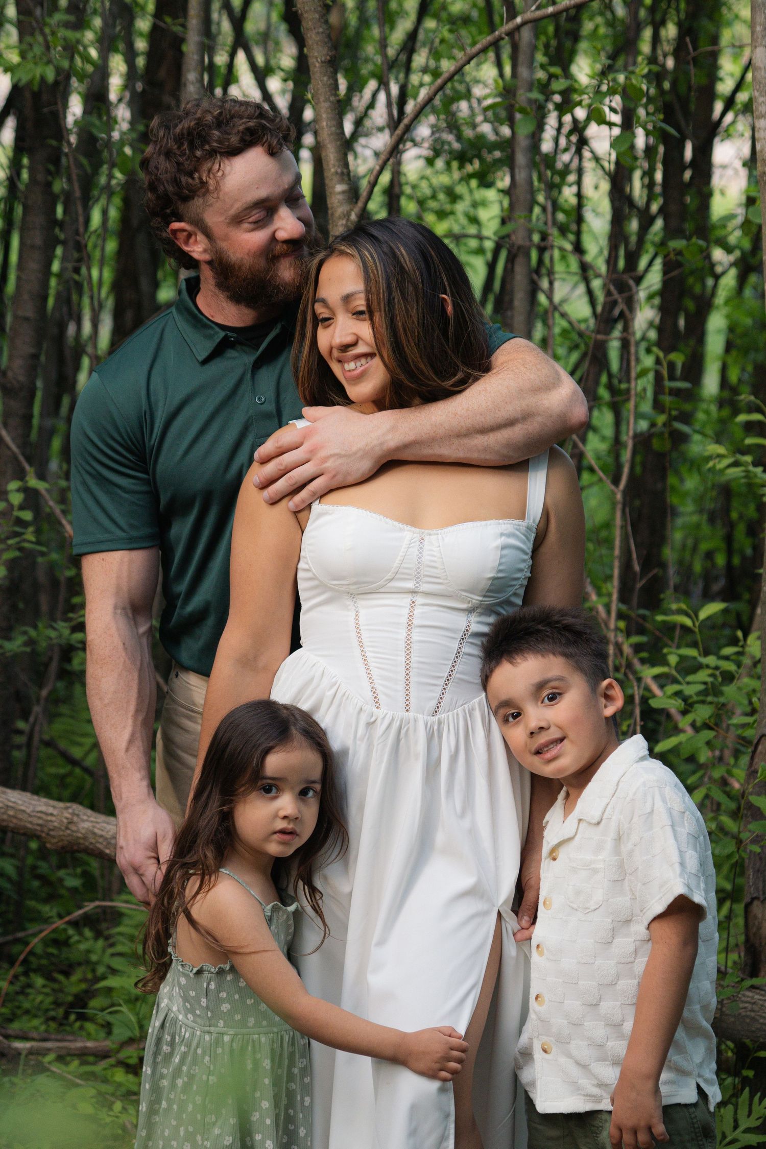 Family portrait moment captured in lush green forest setting.