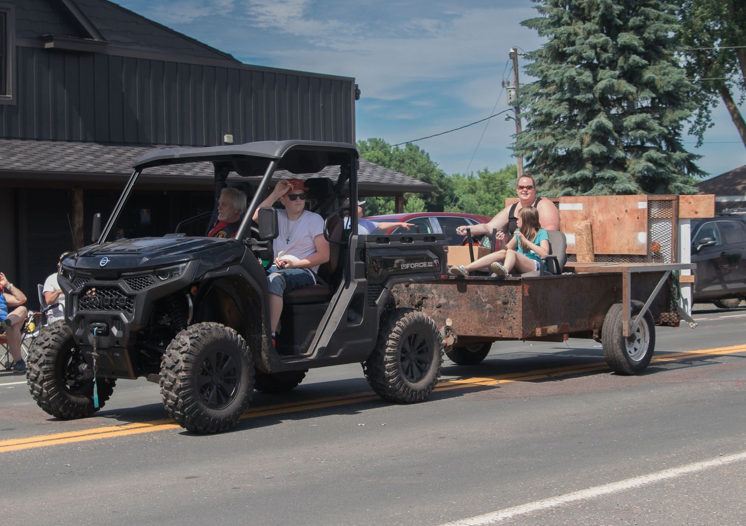 A parade of off-road vehicles and trucks lined up on a sunny street with American flags displayed.