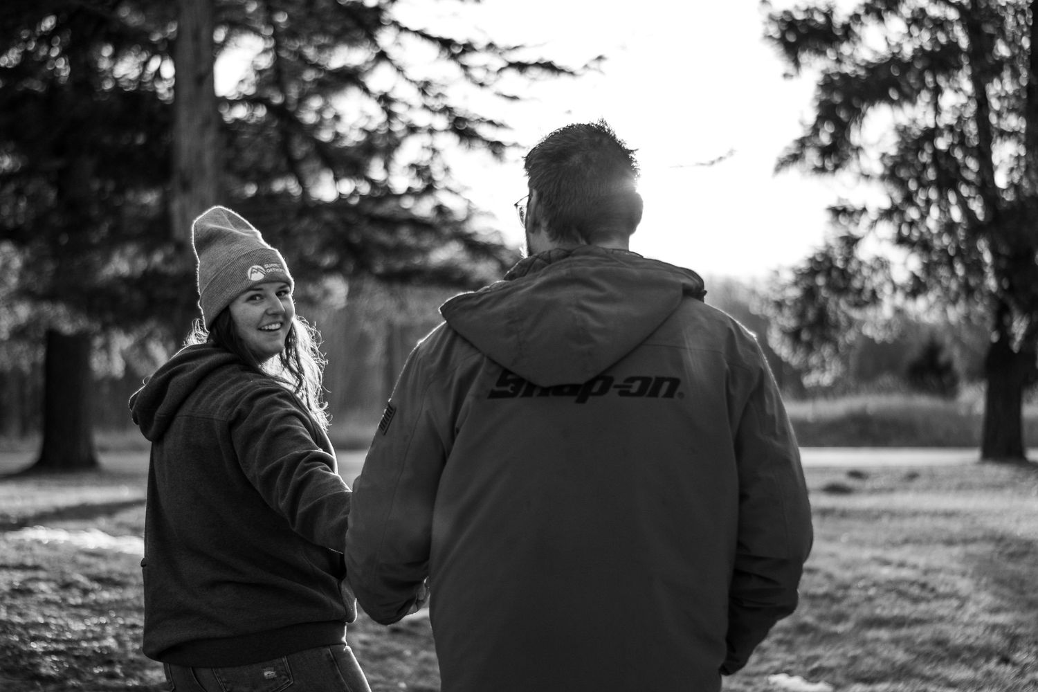 A series of black and white photos showing a couple walking together in a park setting.