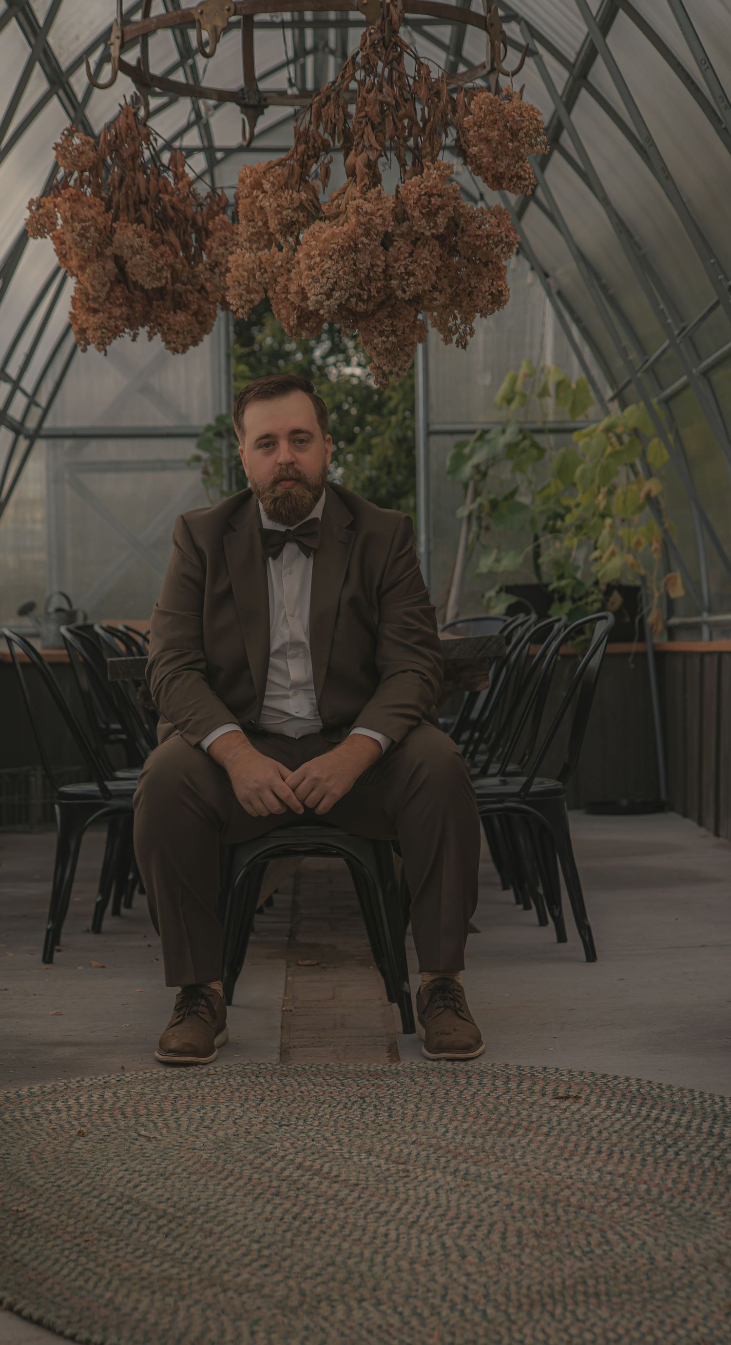 A series of similar photos showing someone seated in a greenhouse with dried flowers hanging overhead.