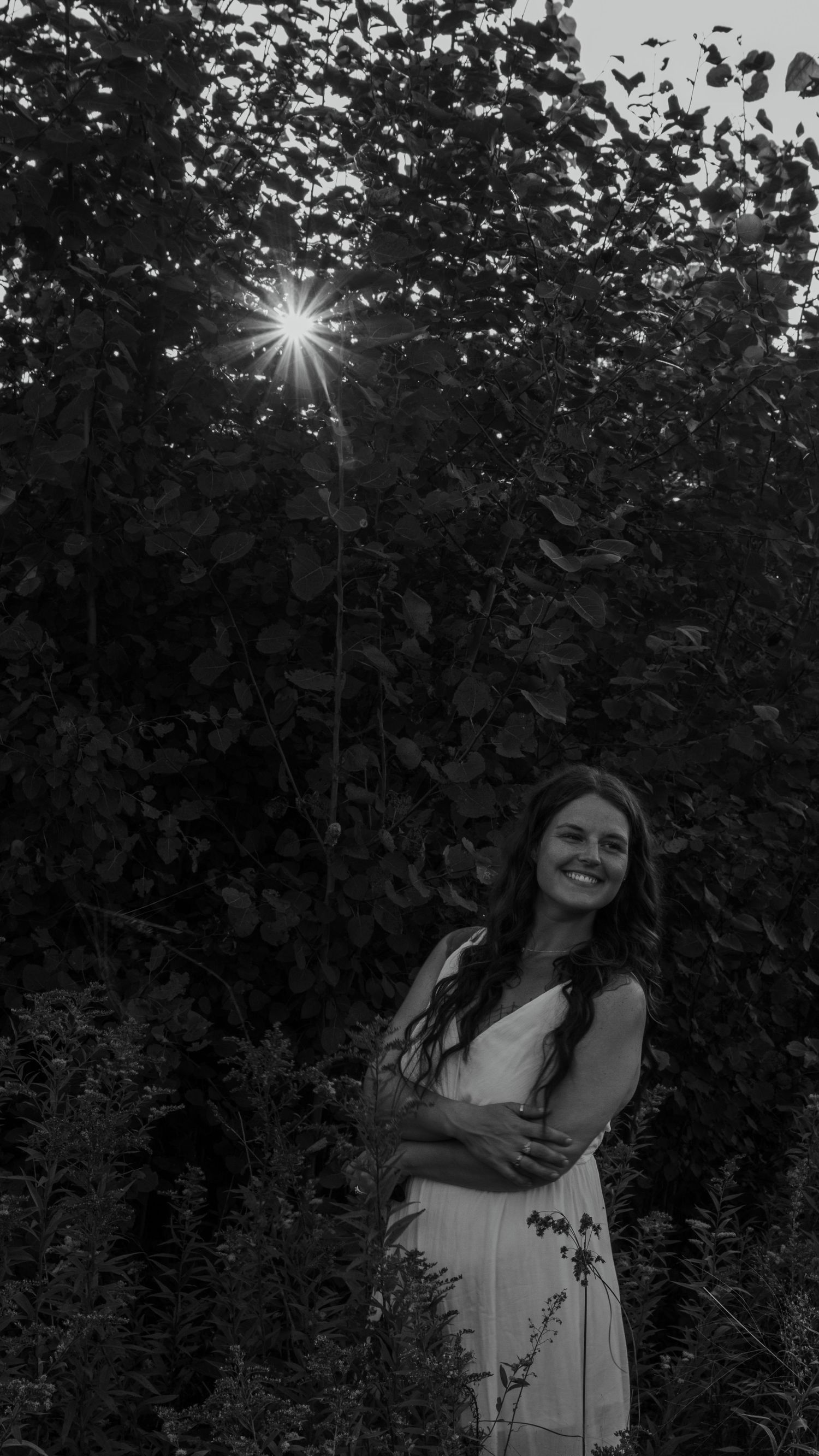A scenic black and white photoshoot amidst lush garden foliage with sunlight peeking through the leaves.