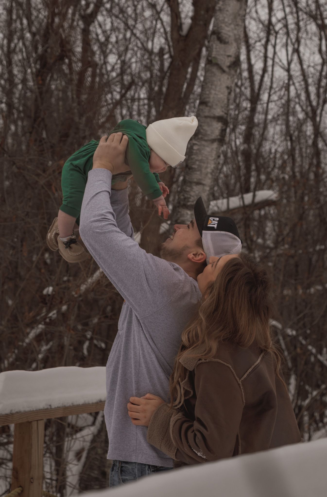 A couple shares a romantic moment in a snowy winter forest setting.