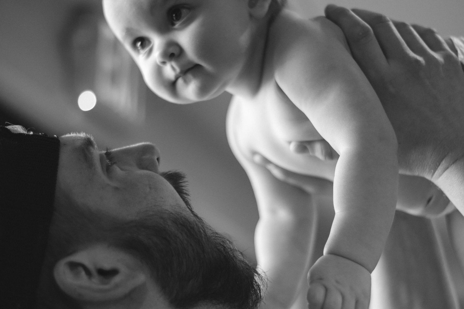 A tender moment between parent and baby in black and white photography.