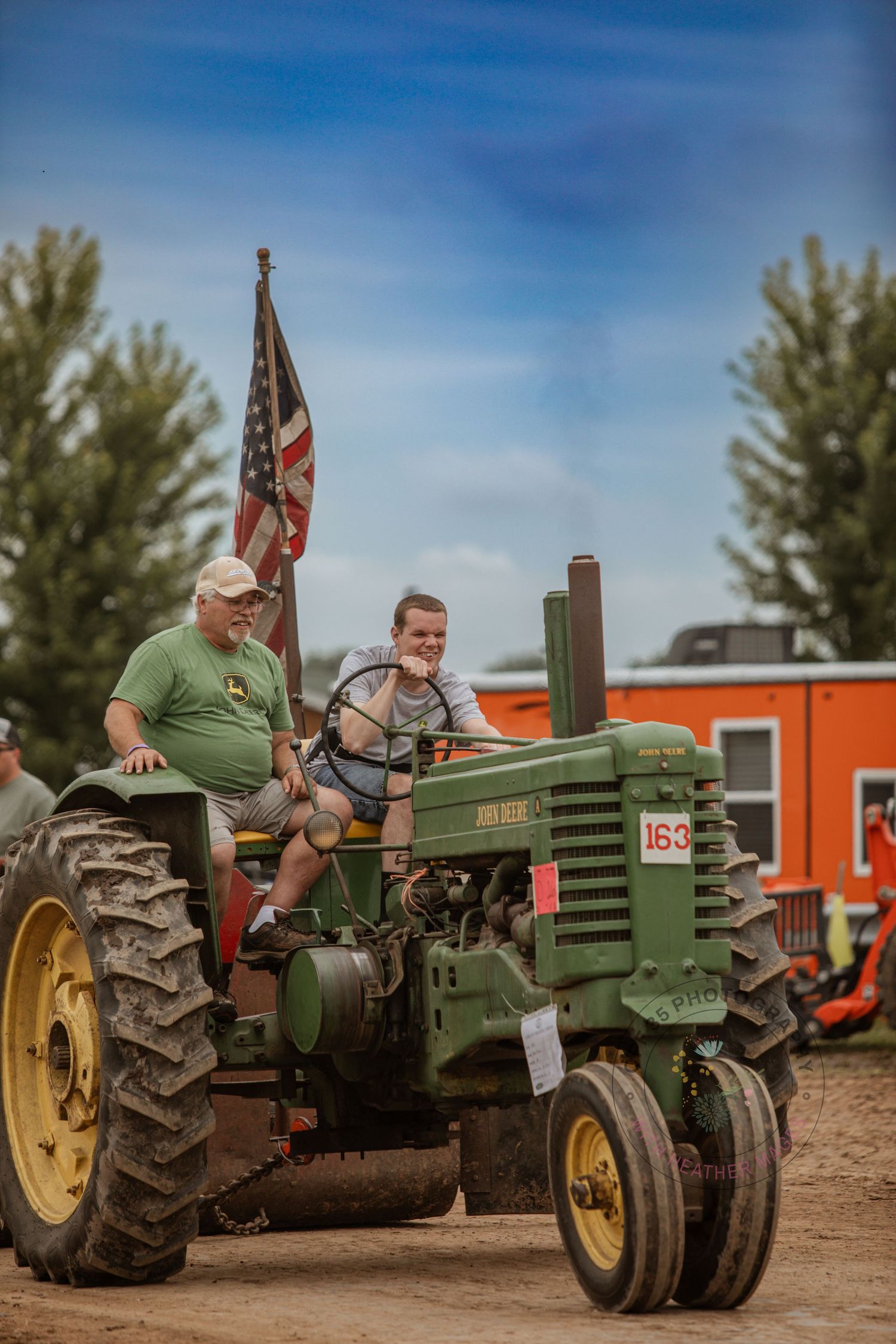 Classic John Deere tractor with American flag displayed at rural community event.