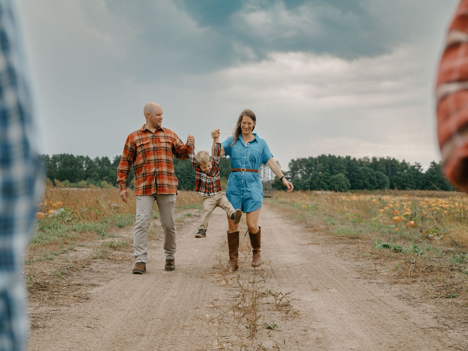 People walking down a dirt path through a rural field on a cloudy day.