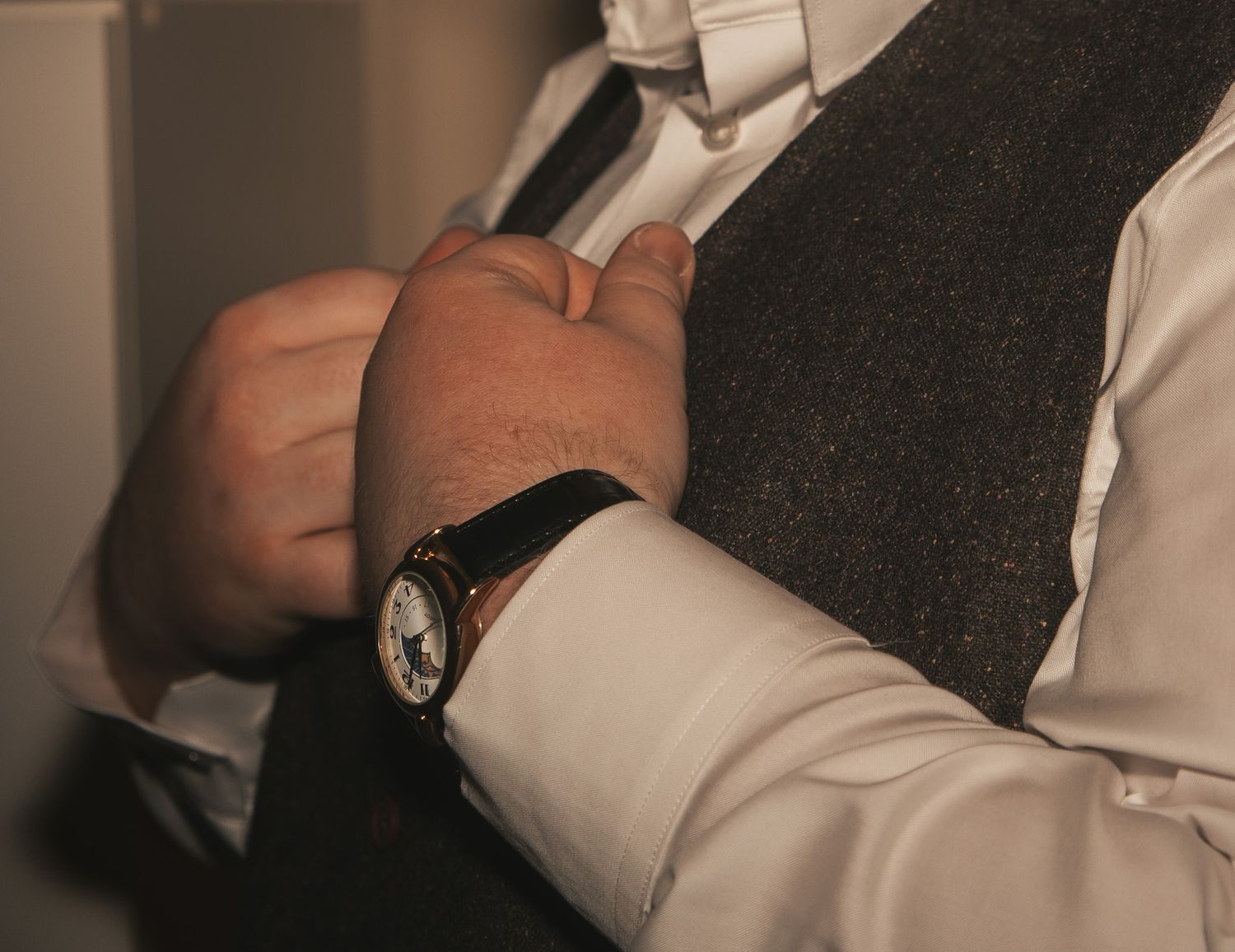 A series of black and white photos showing hands buttoning up a white dress shirt sleeve.