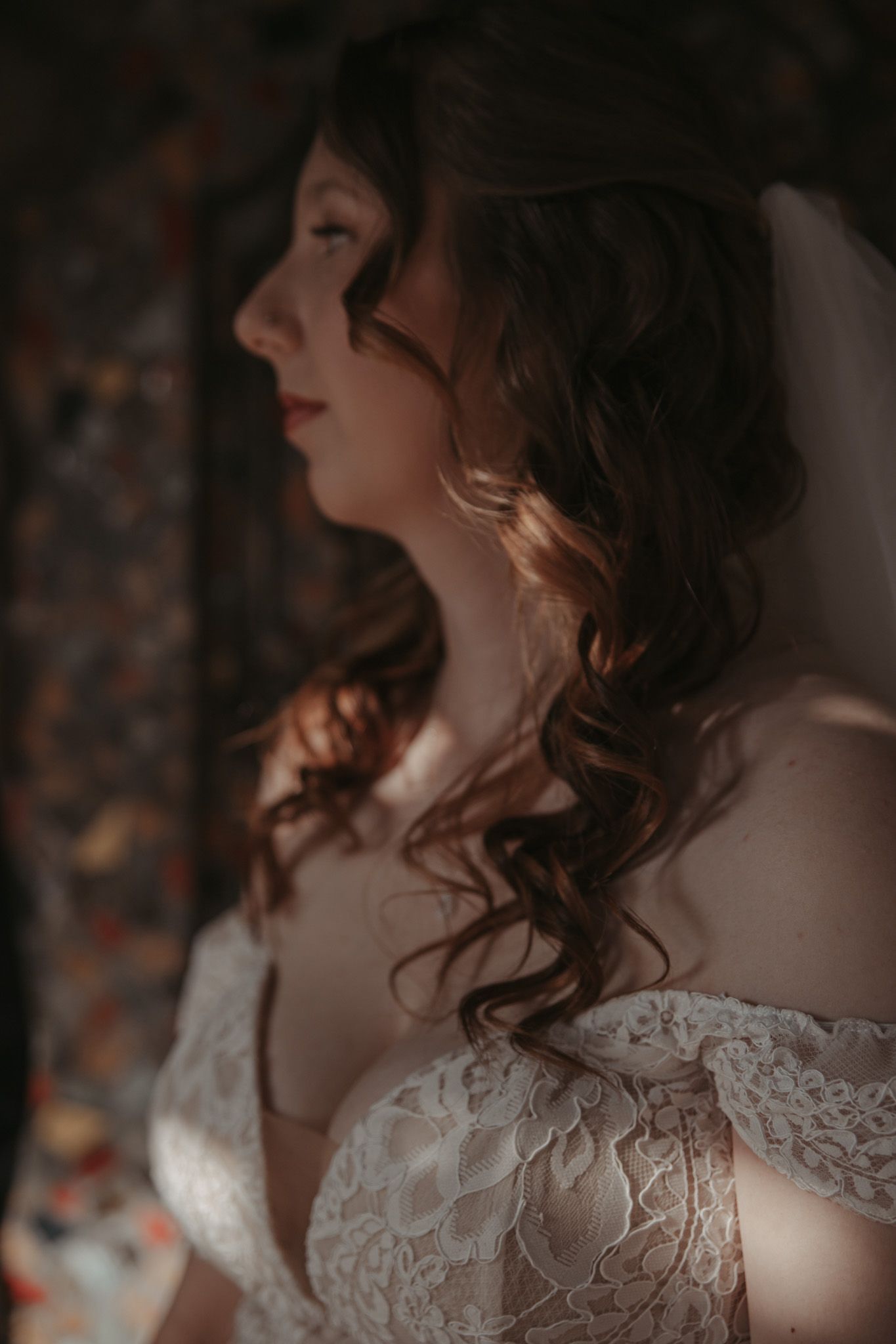Romantic wedding photography showing delicate lace details on a bridal gown in soft, moody lighting.