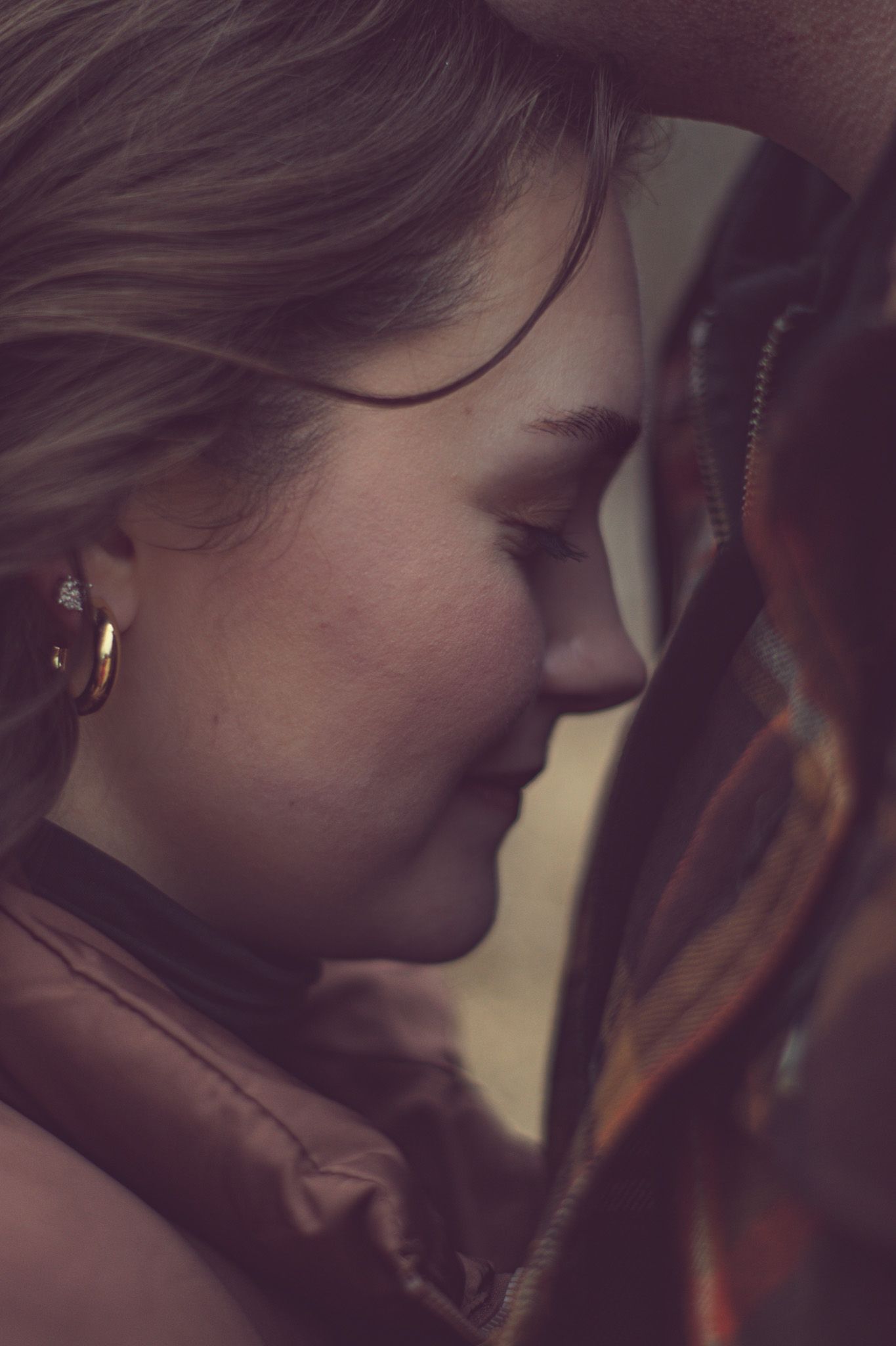 A somber profile shot in warm tones shows a person leaning their head against a wooden surface in shadow.