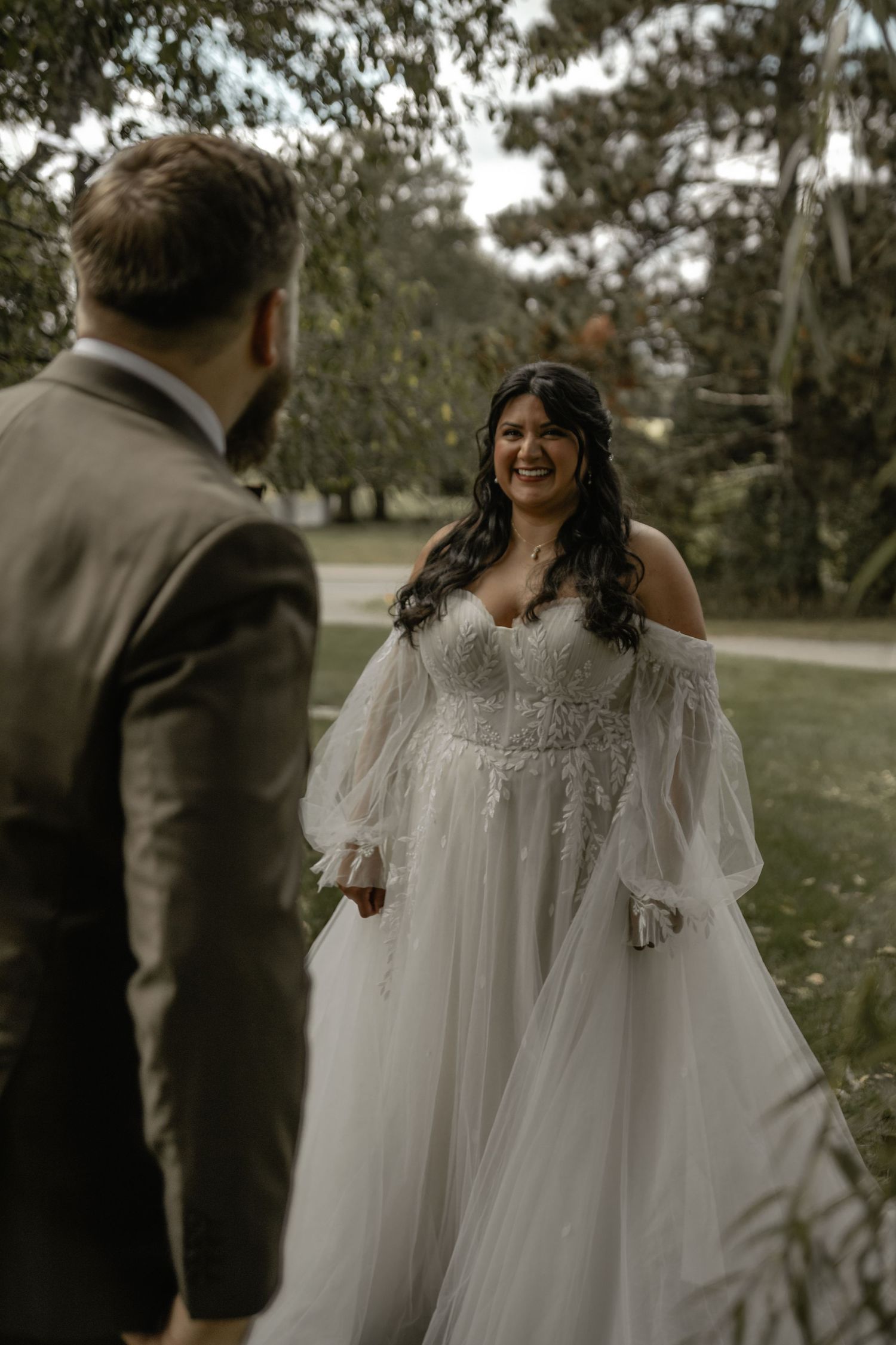 A joyful couple shares a candid moment during their outdoor wedding photoshoot in a natural setting.