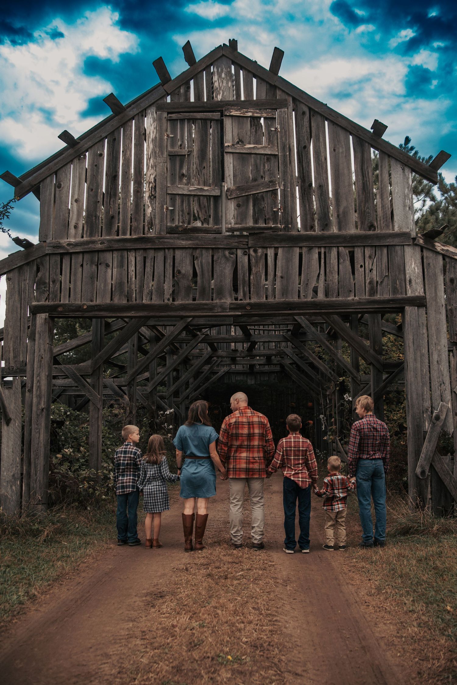 A group stands together in front of a rustic wooden barn under dramatic blue skies in a series of progressive shots.