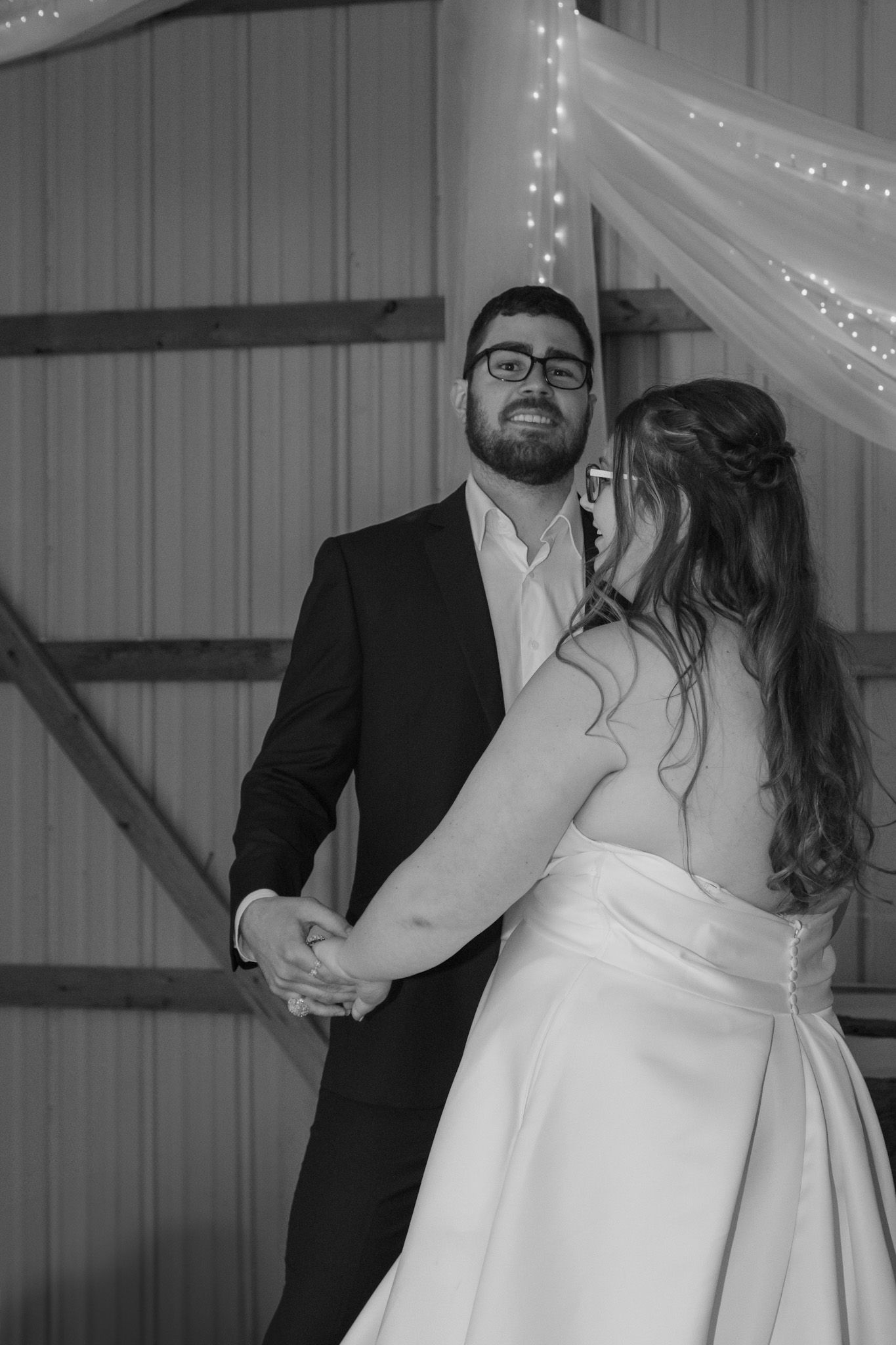 A romantic moment captured in black and white as a bride and groom share a kiss at their wedding reception.