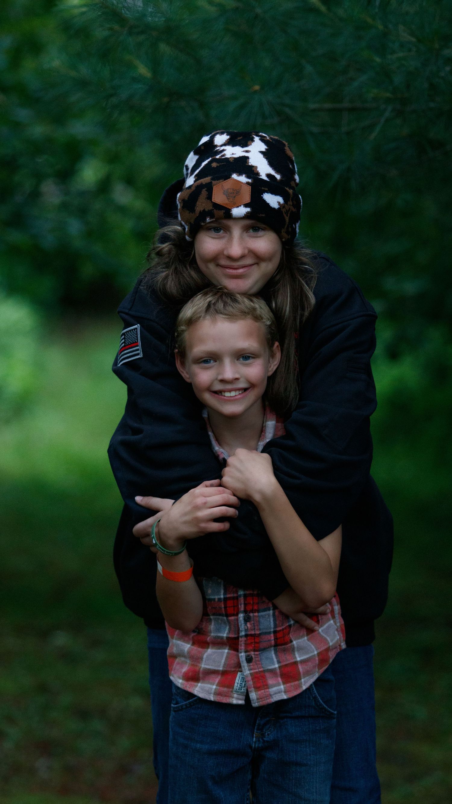 A playful series of four photos showing tender family moments outdoors against a dark green forest backdrop.