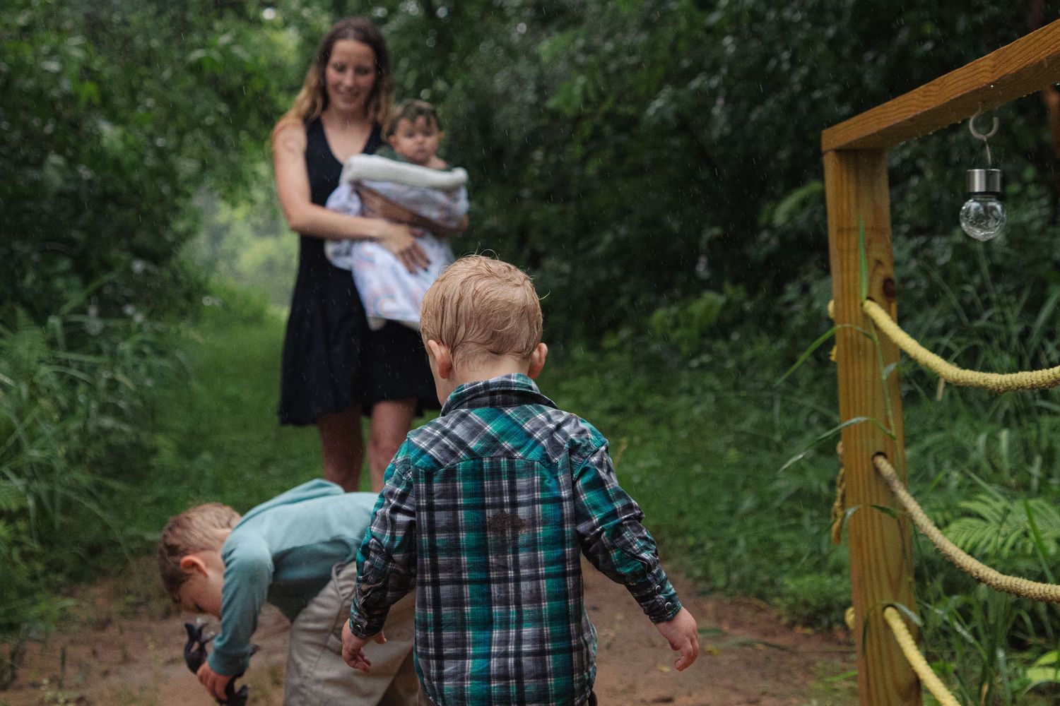 Children run through a lush forest path while playing outdoors on a summer day.