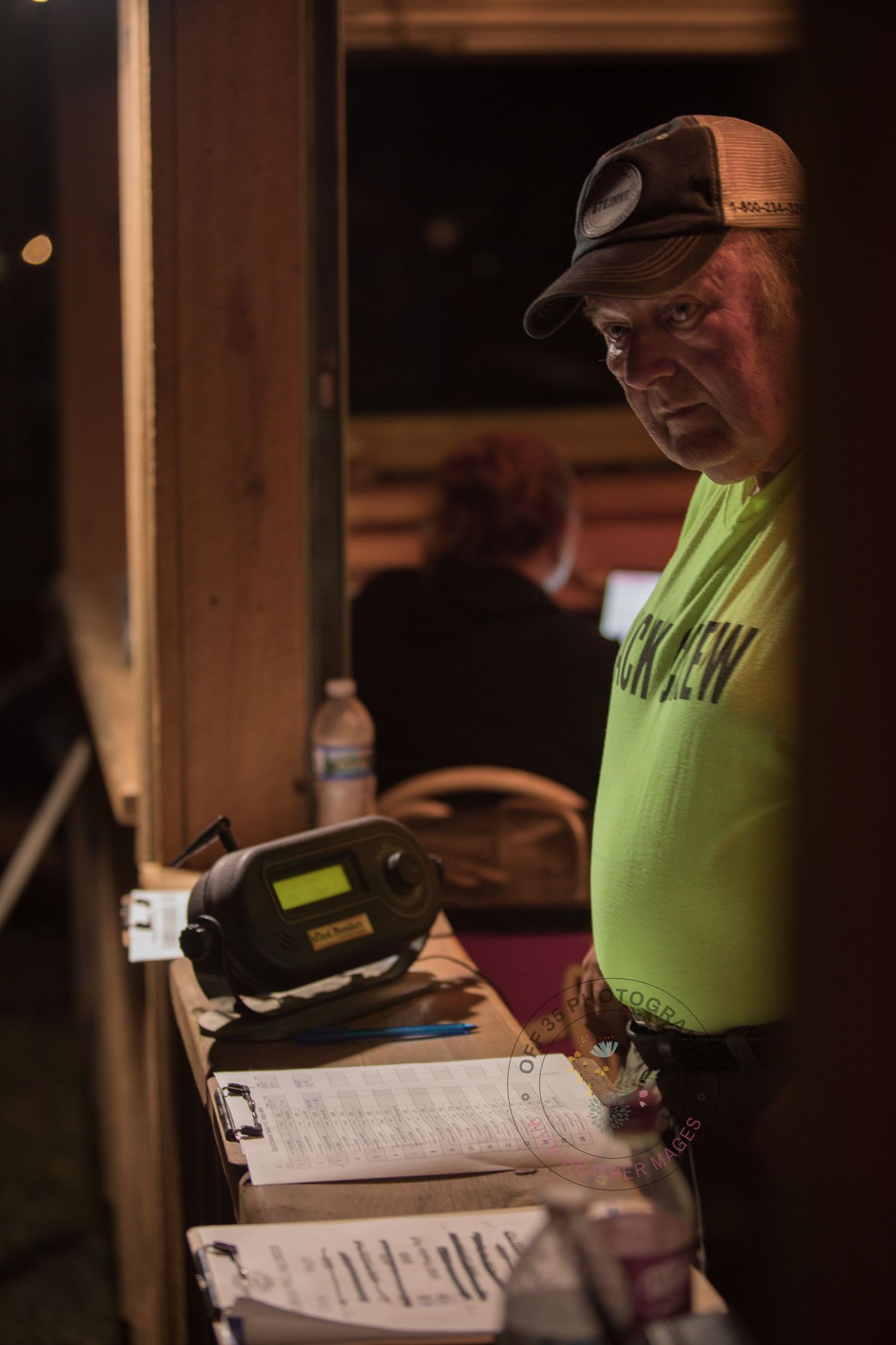Staff member in neon yellow shirt reviews paperwork at a dimly lit desk during nighttime operations.