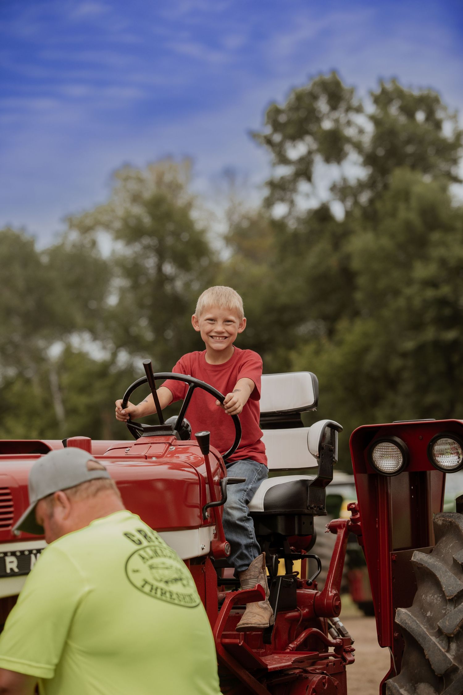 A series of five photos showing a child in a red shirt playing on a red tractor in an outdoor setting.