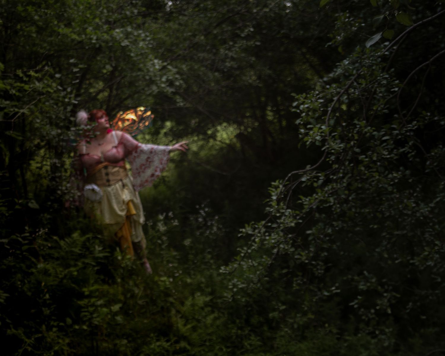 Ethereal fairy figure floating in a dark enchanted forest with glowing magical lights around them.