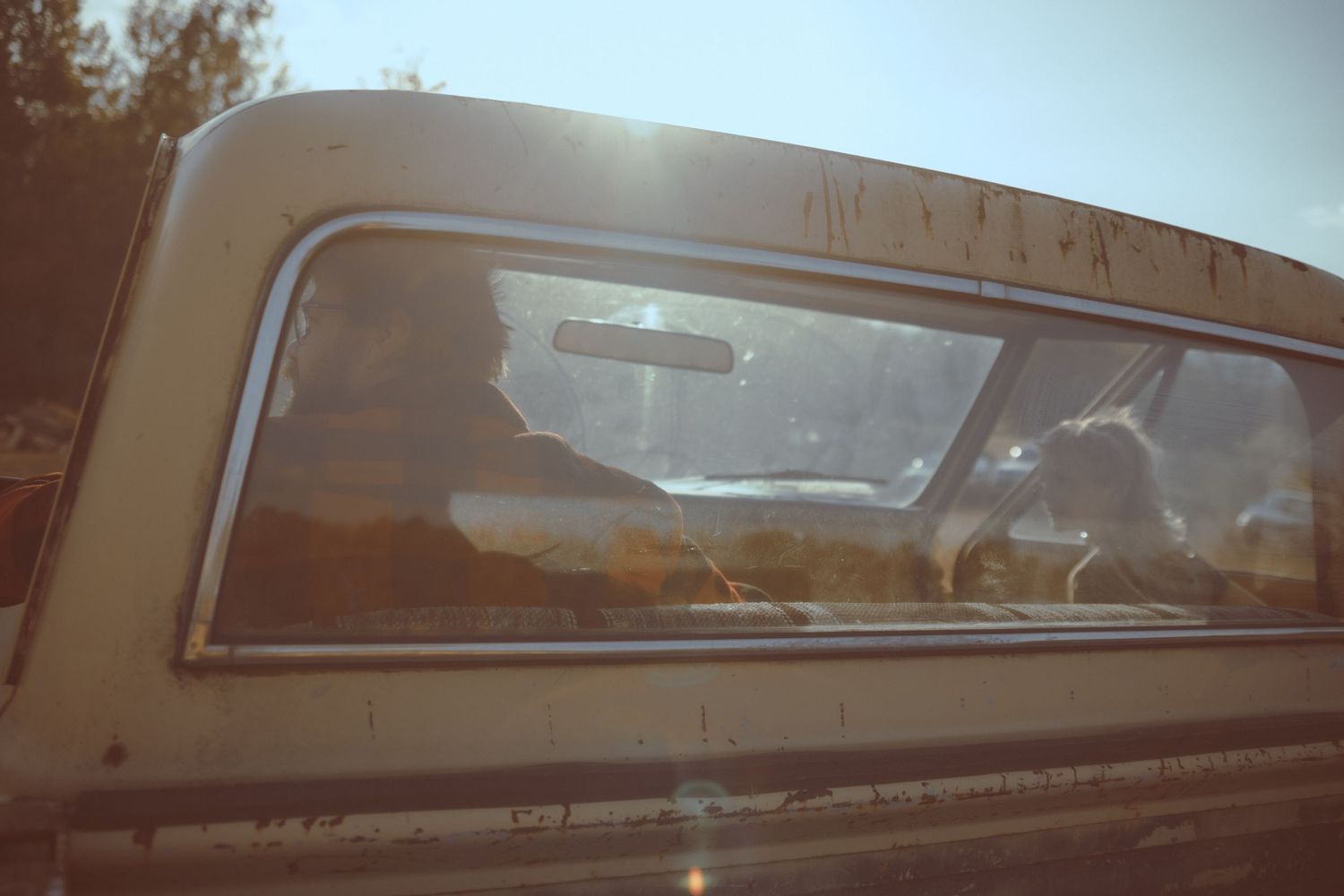 Vintage brown car with chrome trim and curved glass windows parked in front of a building.