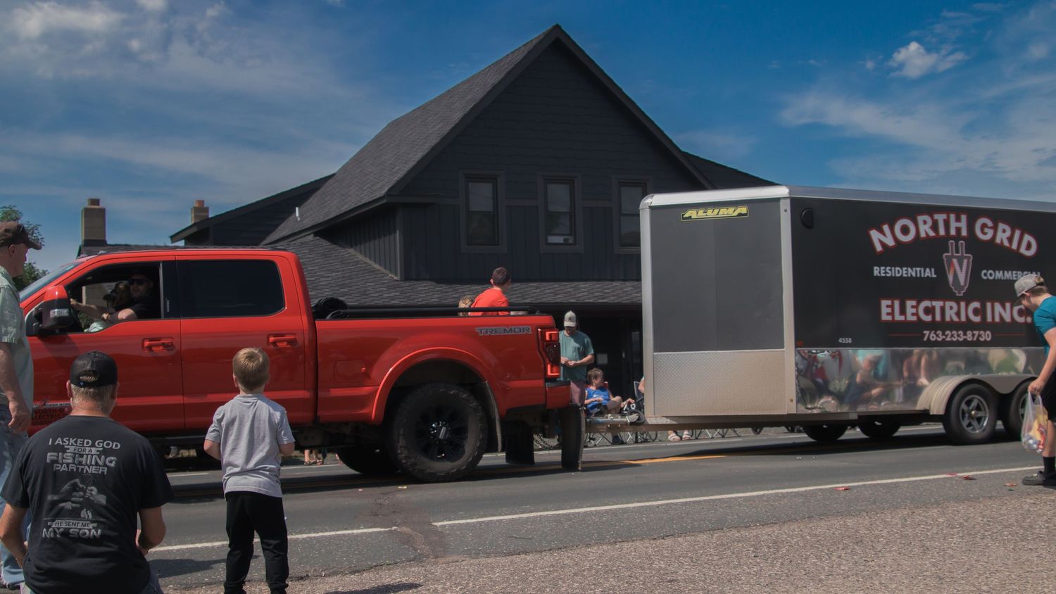 Panoramic view of classic cars and trucks on display at an outdoor event with dark buildings in background.