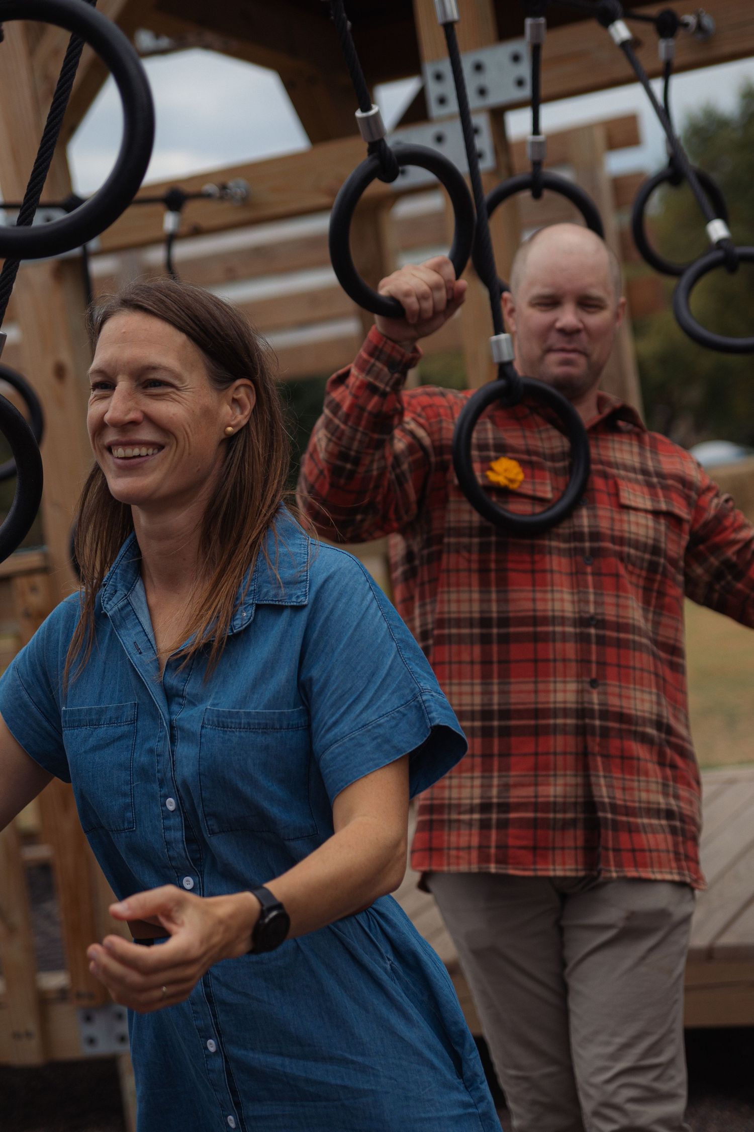 People enjoying a playful moment at a playground with someone wearing a denim shirt and plaid flannel.