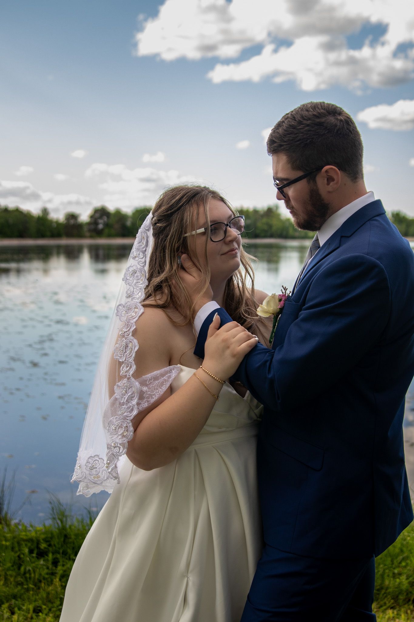 A romantic wedding couple shares an intimate moment by a serene lake on their special day.