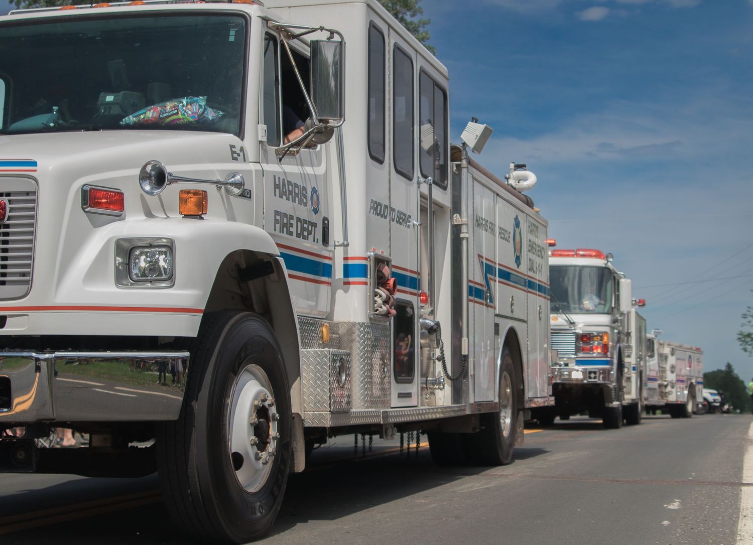 Row of white emergency response vehicles parked in a line under blue sky.