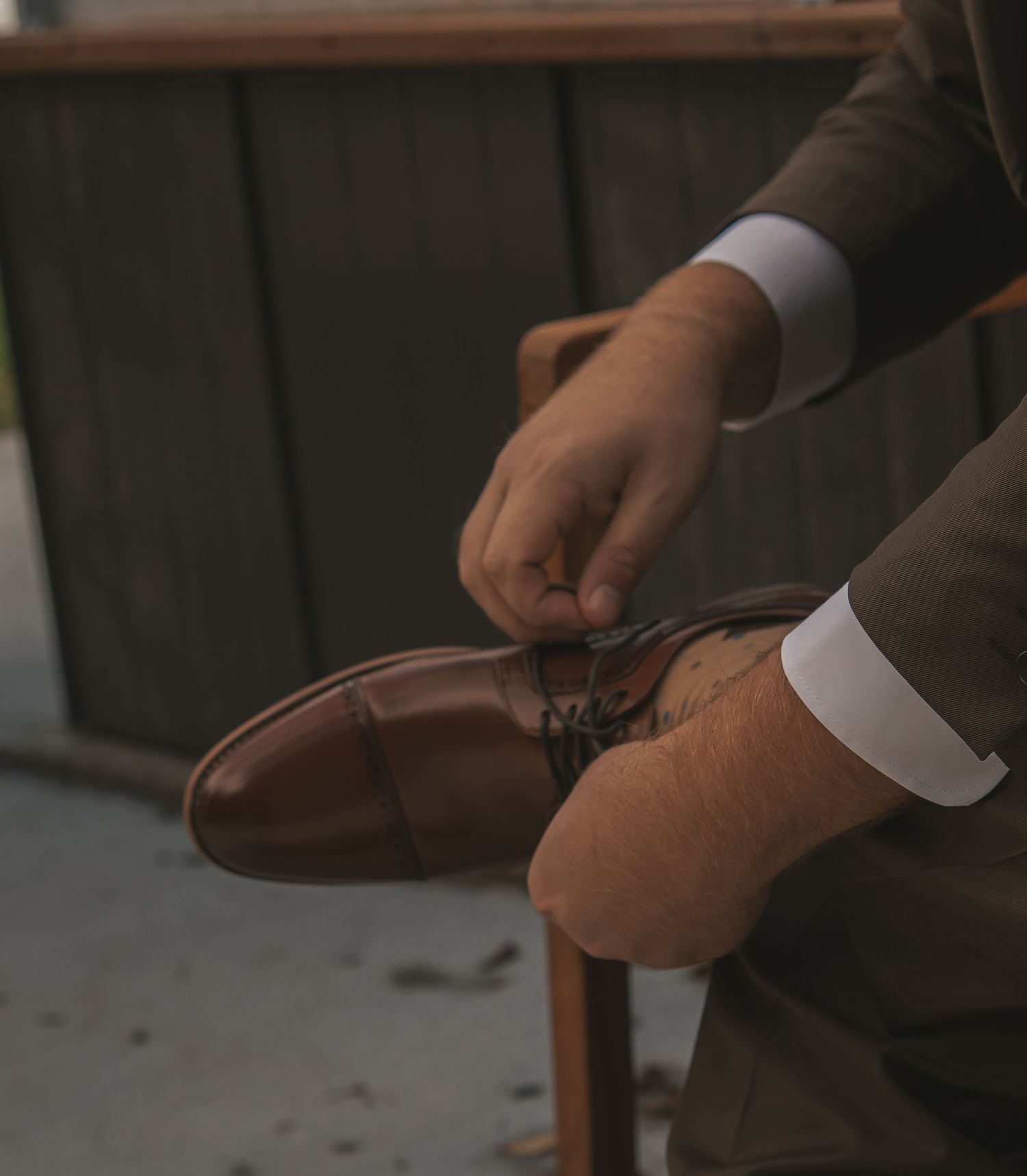 Close-up shot of hands adjusting a brown leather watch strap against a dark background.
