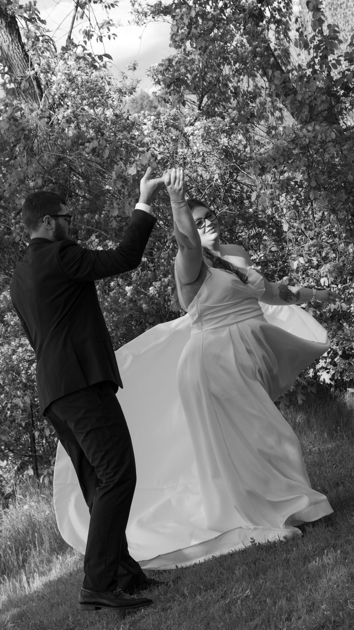 A black and white photo series shows a couple dancing on a grassy hillside, with the bride's white dress flowing dramatically.
