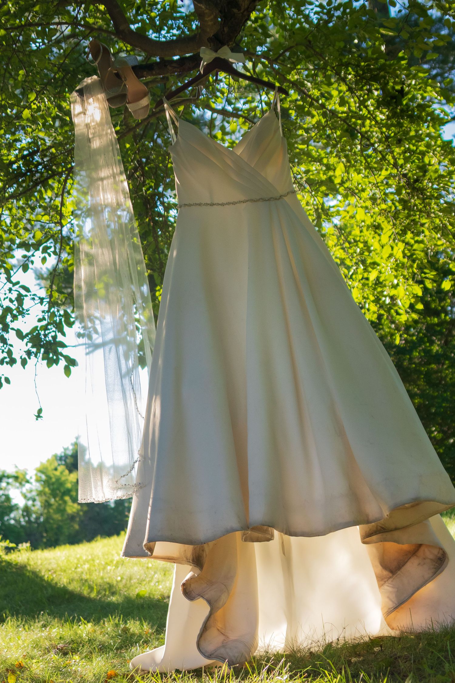 White sheets hanging on clothesline sway gently in breeze against sunny green garden background.