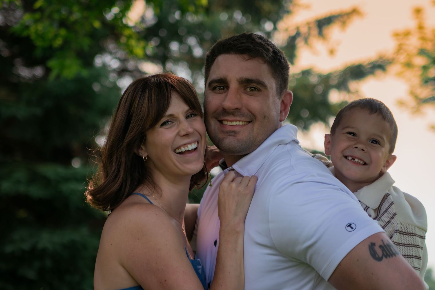 Family shares cheerful moment together outdoors during golden hour photo session.