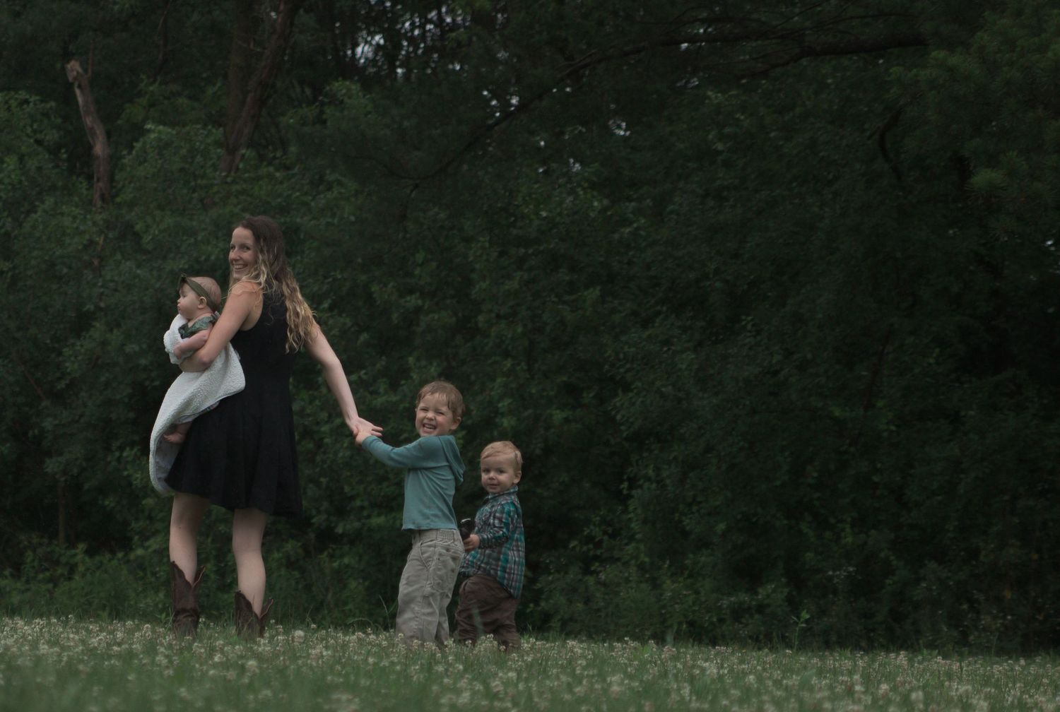 Two people dancing together joyfully in a grassy outdoor setting surrounded by trees.