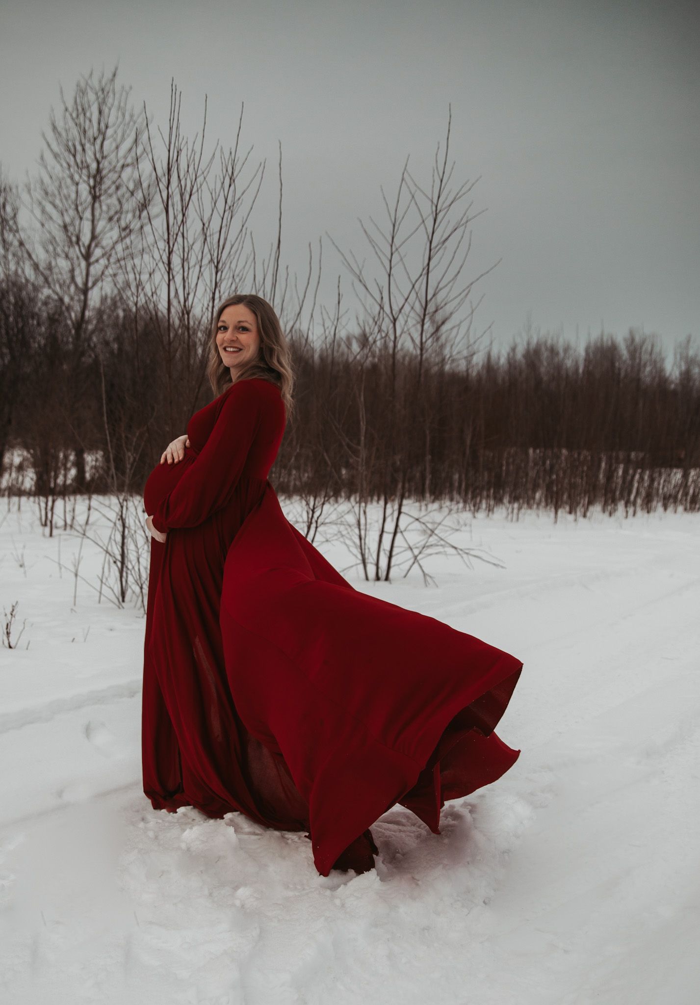 Flowing red dress twirls dramatically against stark white snow-covered winter landscape.
