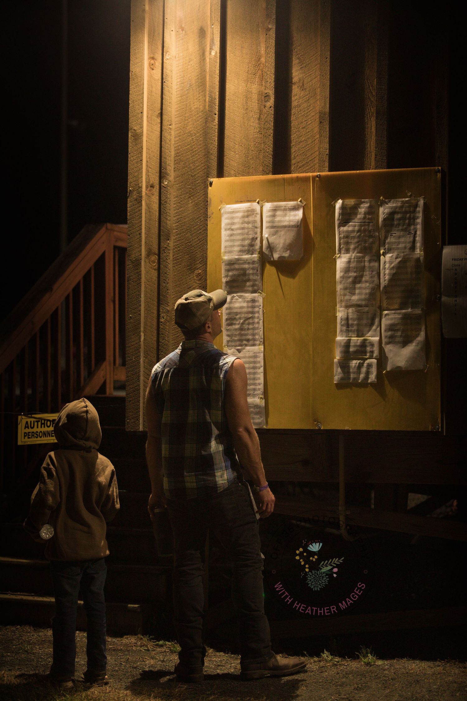 People examining posted documents on a wall at night with flashlights.