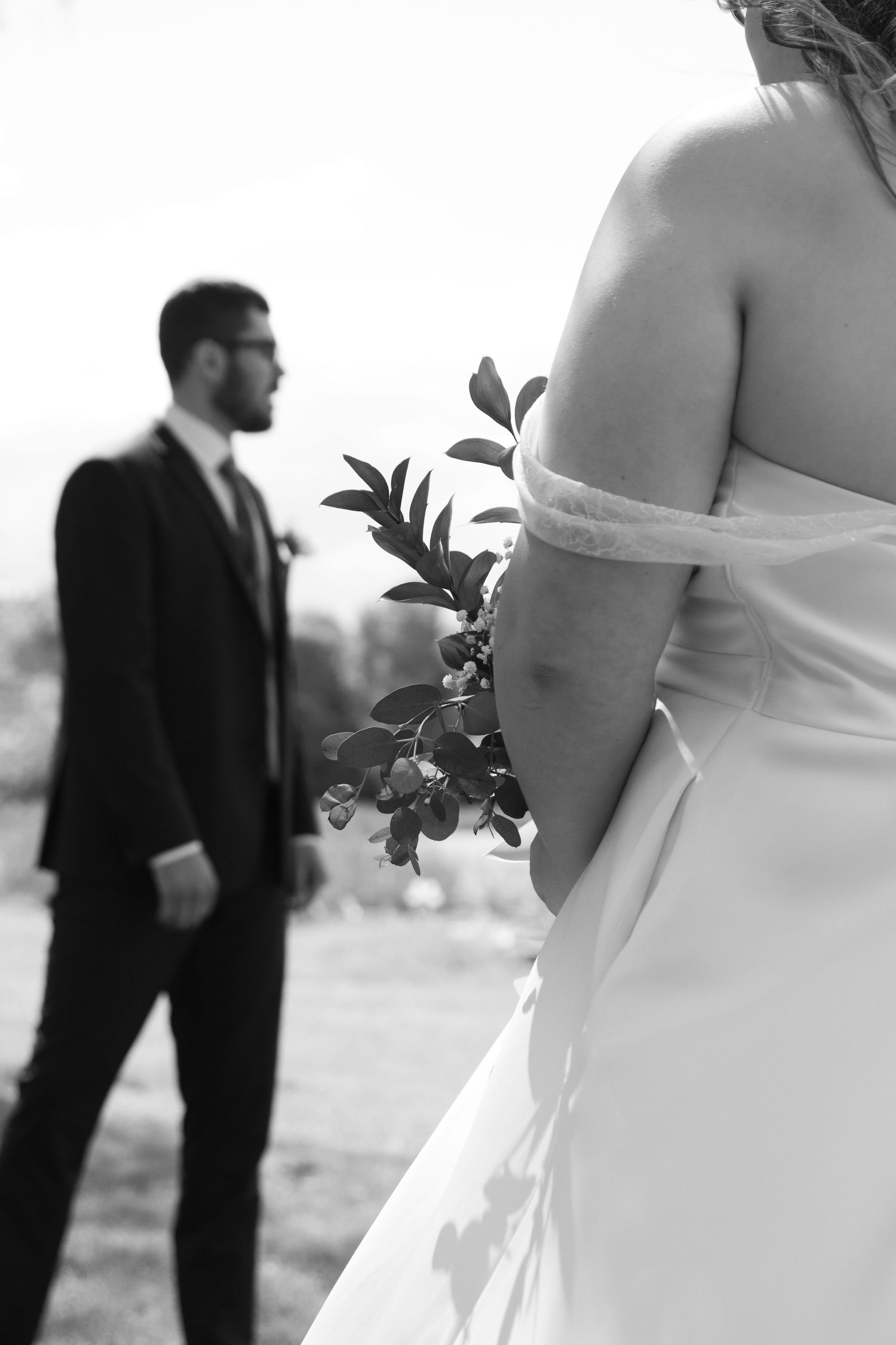 Artistic black and white wedding photo showing contrasting silhouettes and floral details against a bright background.