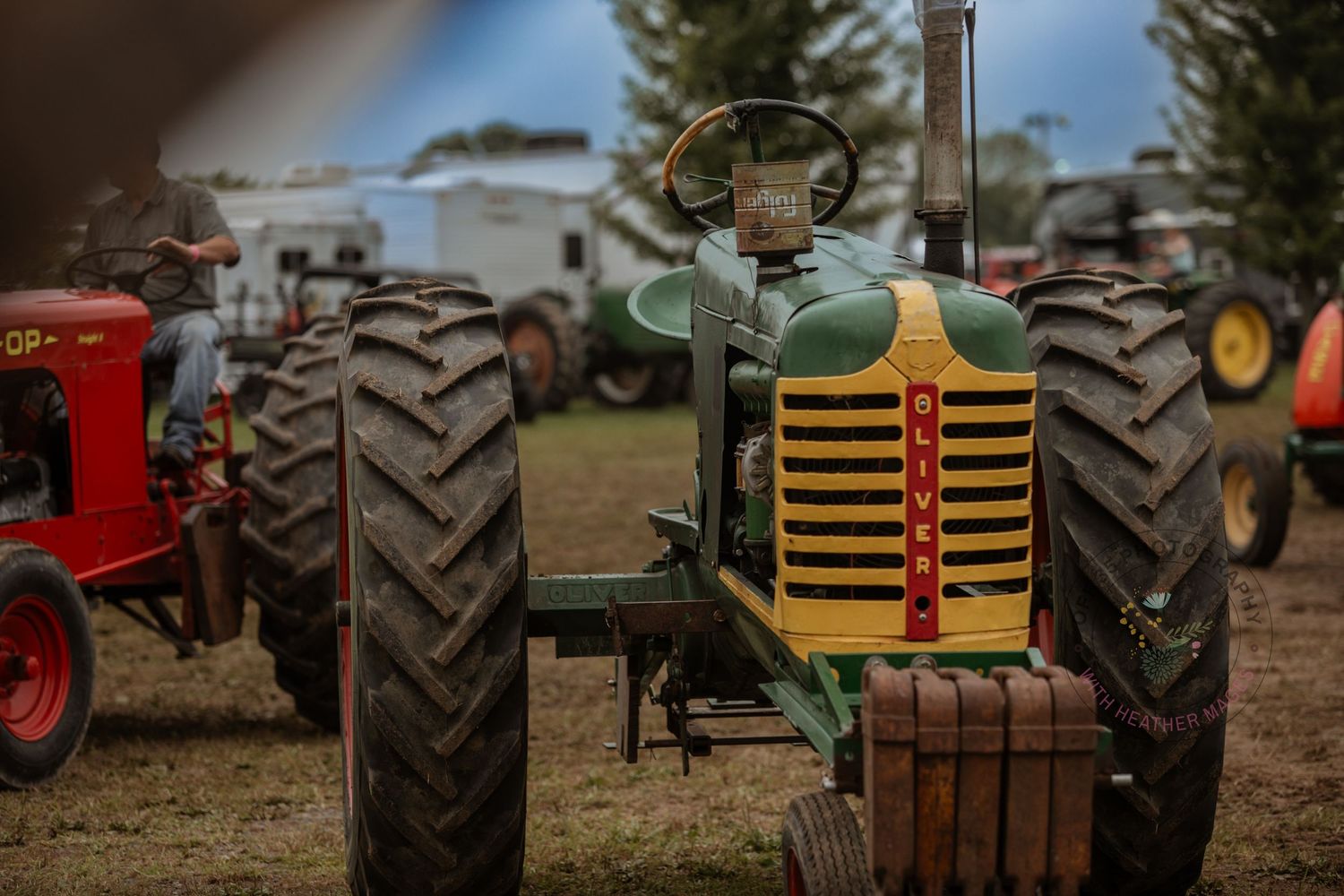 Vintage green and yellow tractor with large tires displayed at an outdoor farm equipment show.