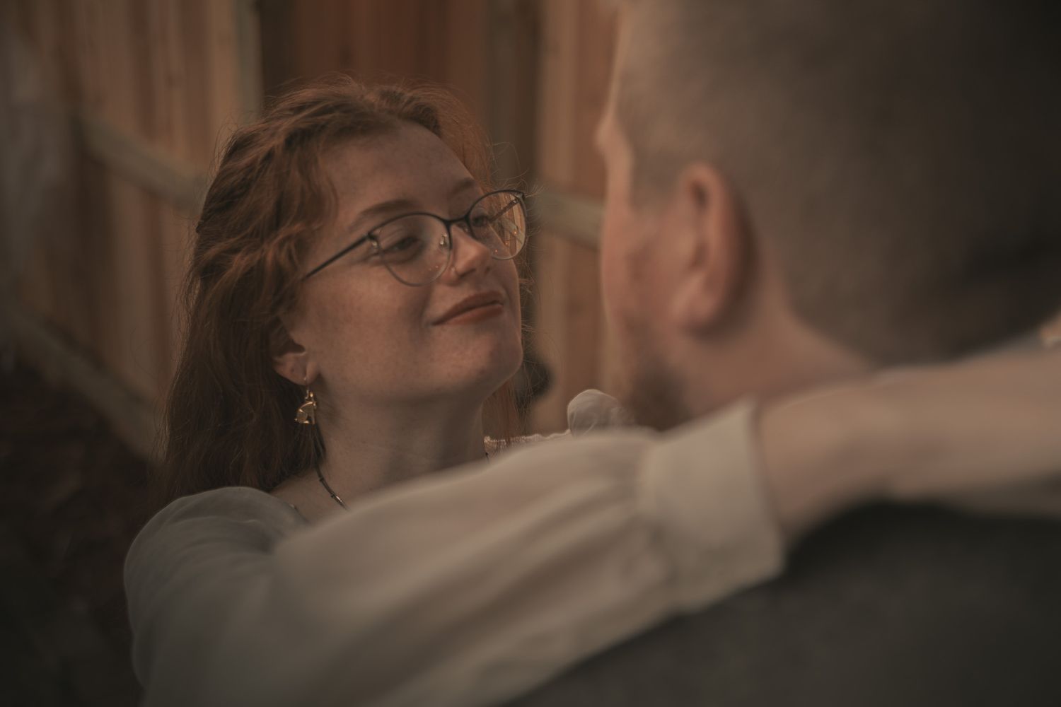 A romantic couple in formal attire dance together with soft lighting creating an intimate atmosphere.