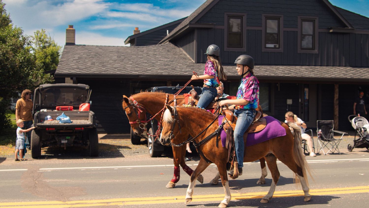 Horse riders and buildings visible at a western-style venue under blue skies.