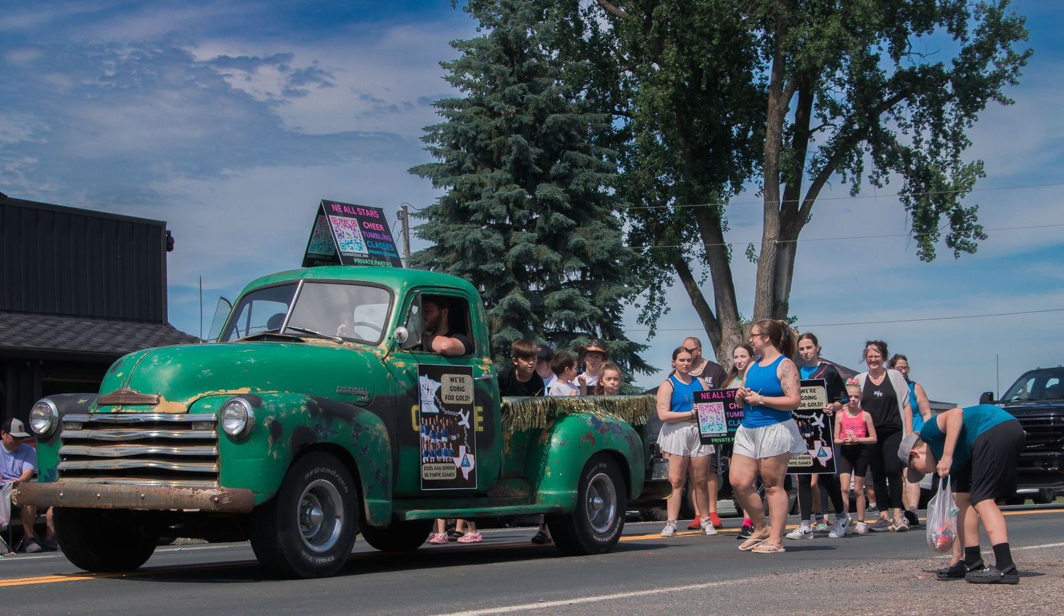 A vintage green convertible classic car displayed at an outdoor car show on a sunny summer day.