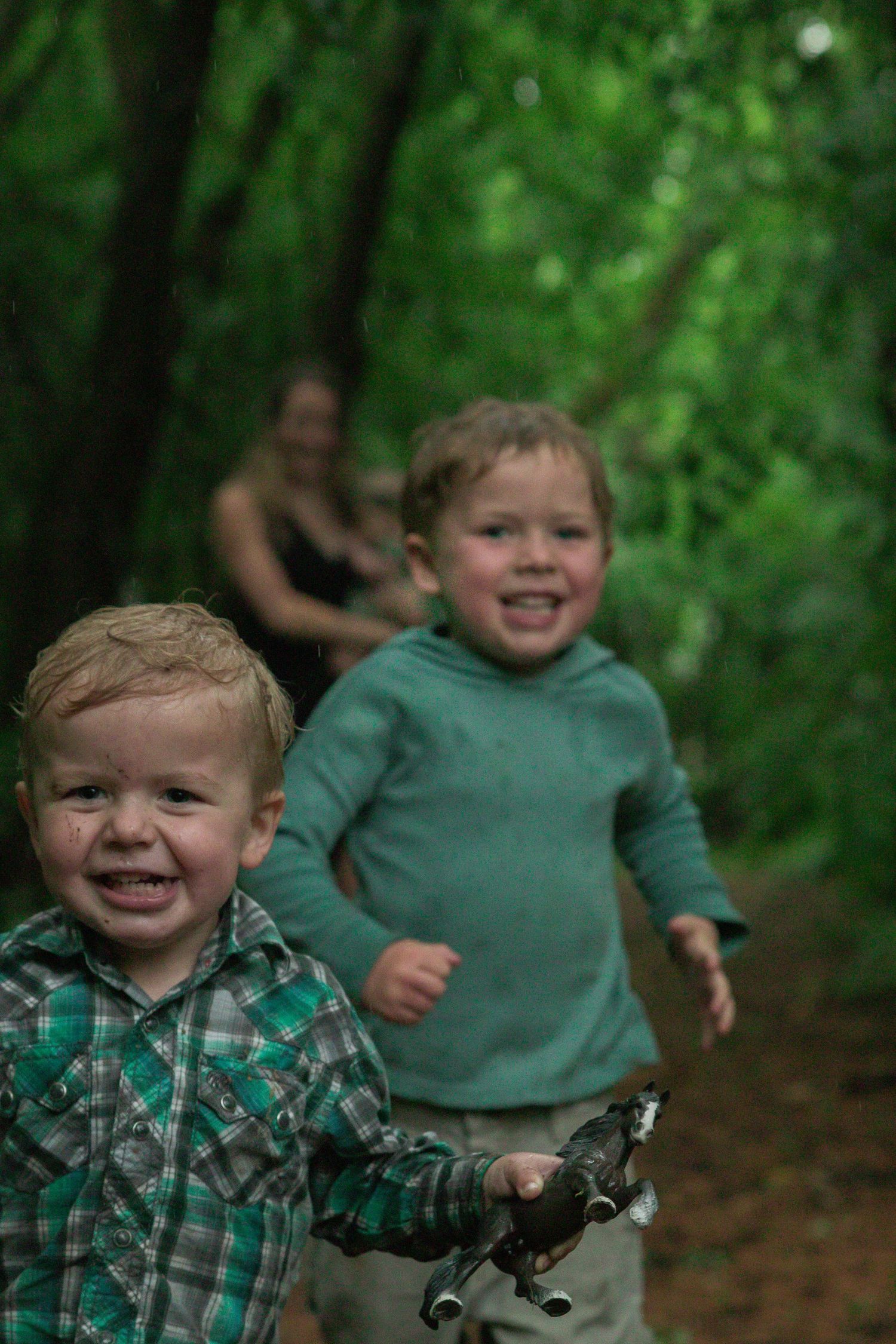 Two children playfully chase each other along a wooded pathway during outdoor adventures.