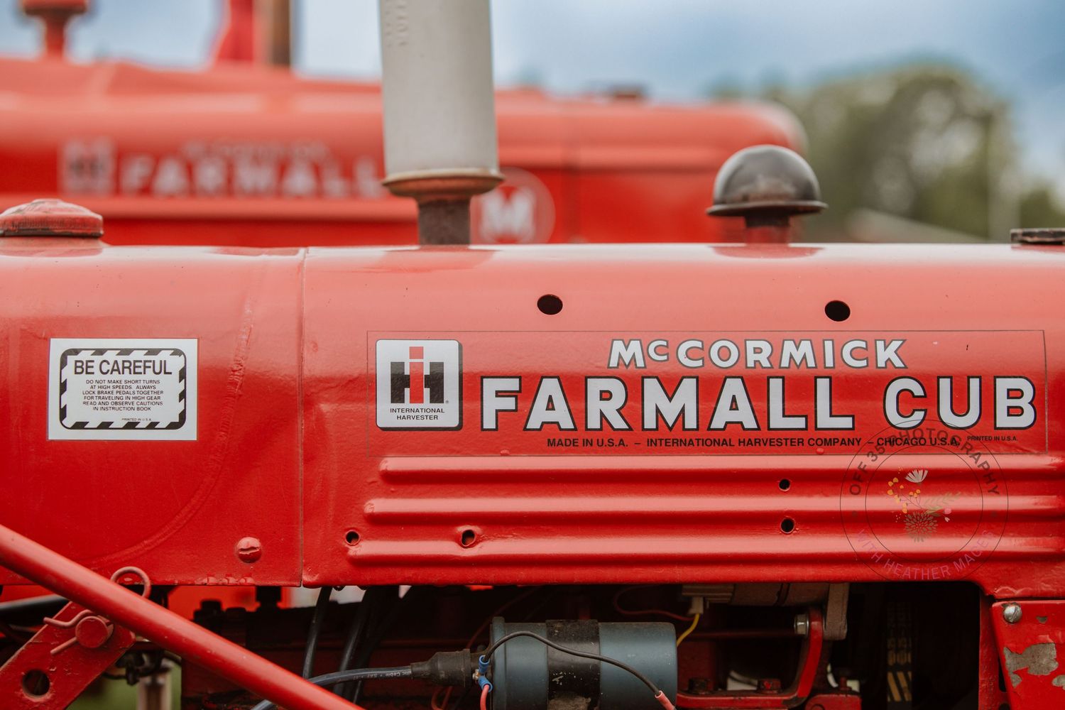 Vintage red Farmall tractors and McCormick equipment displayed in a row at an outdoor agricultural show.