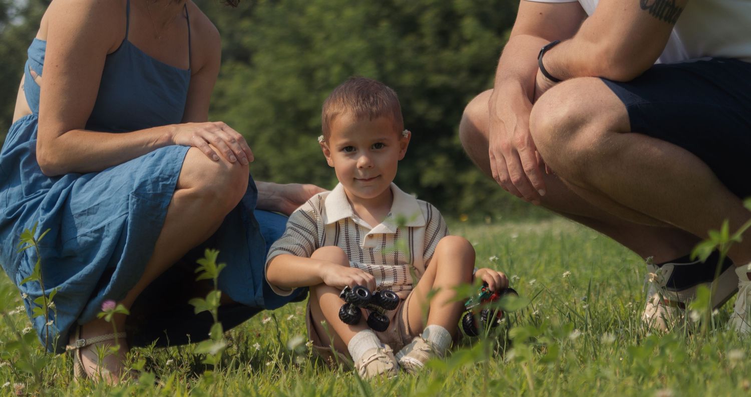 Children gather around to examine insects and bugs in the grass during an outdoor nature exploration activity.
