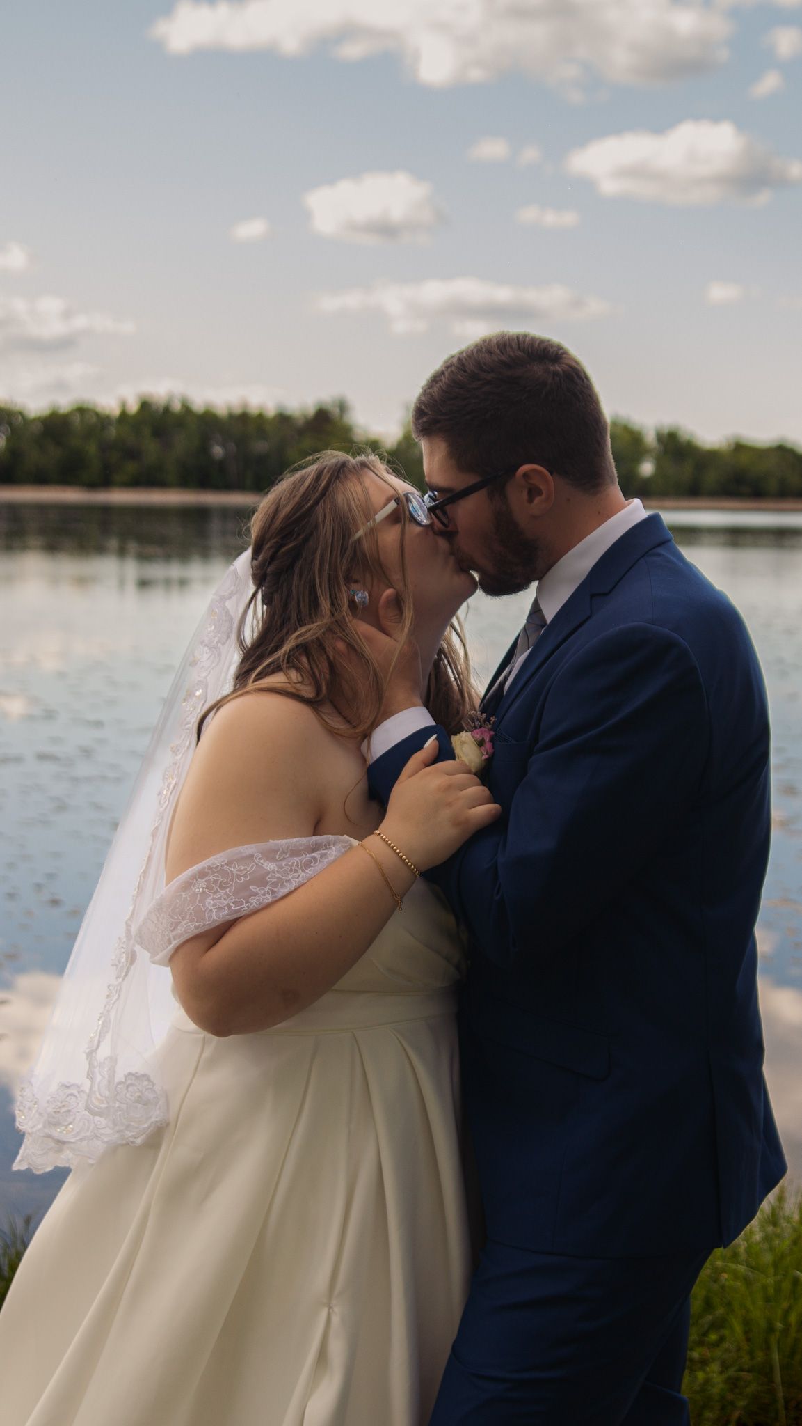 A romantic series of wedding photos shows the newlyweds kissing by a serene lake on their special day.