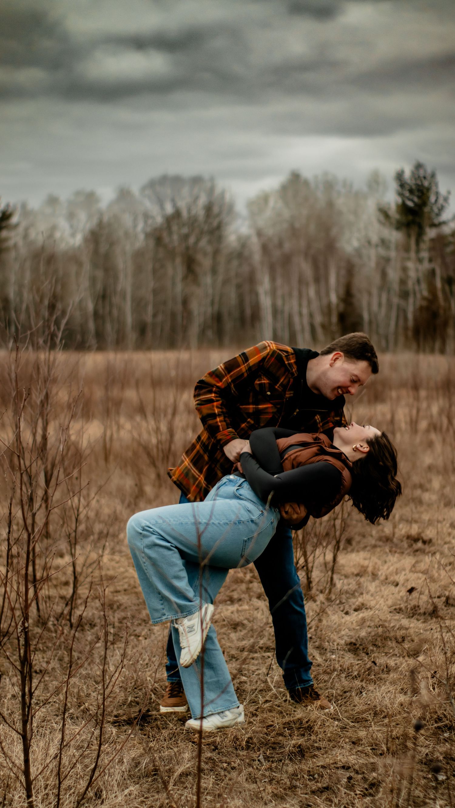 A romantic dip pose between two people in a rural autumn field.